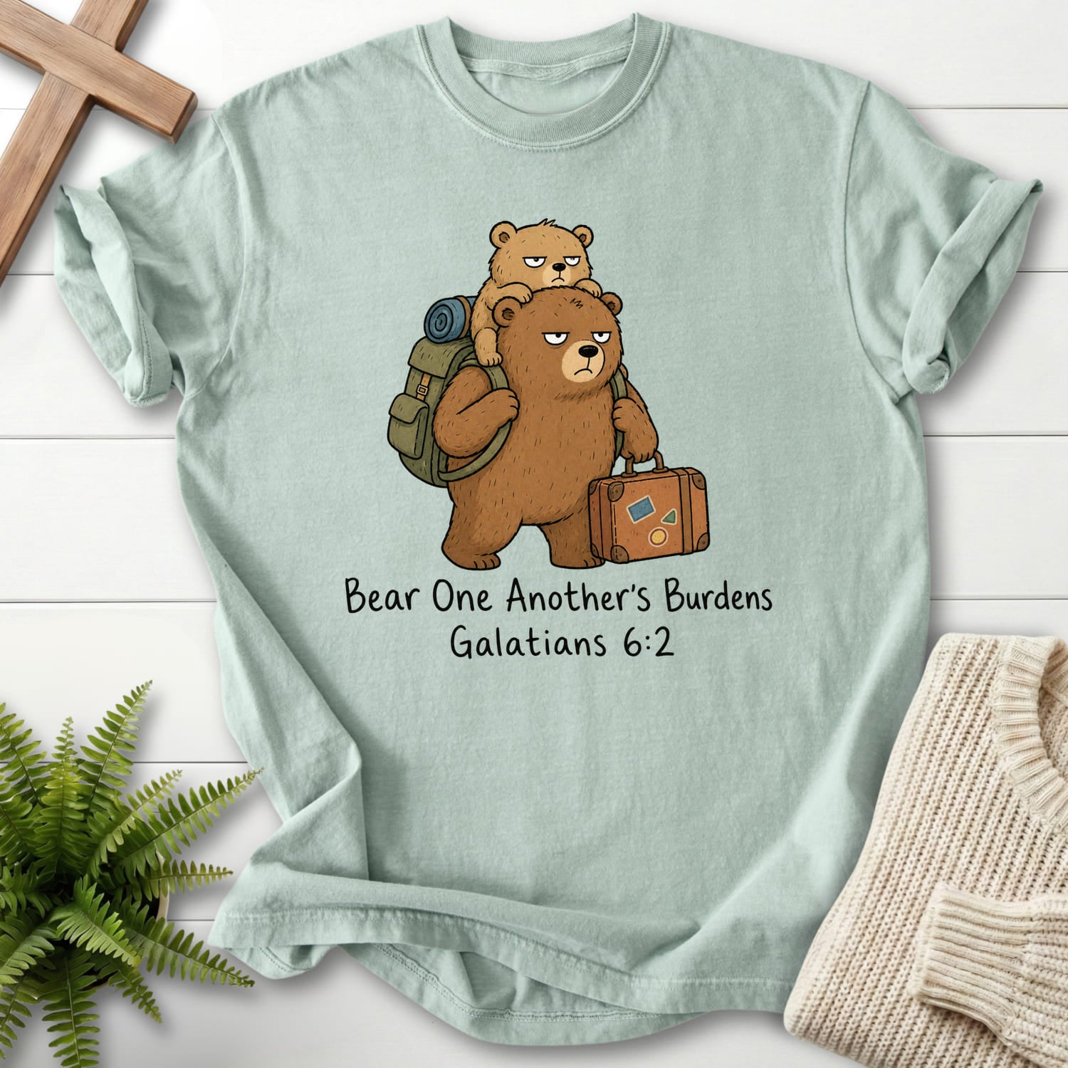 Flat lay of a Bay Christian graphic tee featuring "Bear One Another's Burdens T-Shirt" Galatians 6:2.