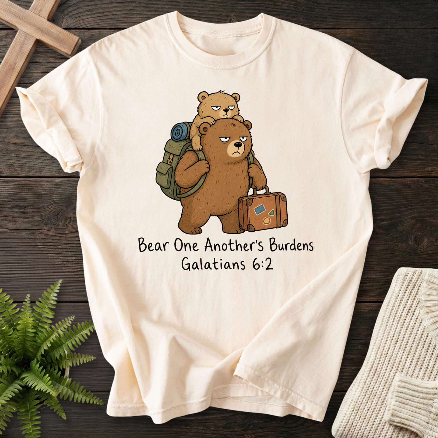 Flatlay of an Ivory Christian t-shirt for women with "Bear One Another's Burdens T-Shirt" Galatians 6:2 From Printify.