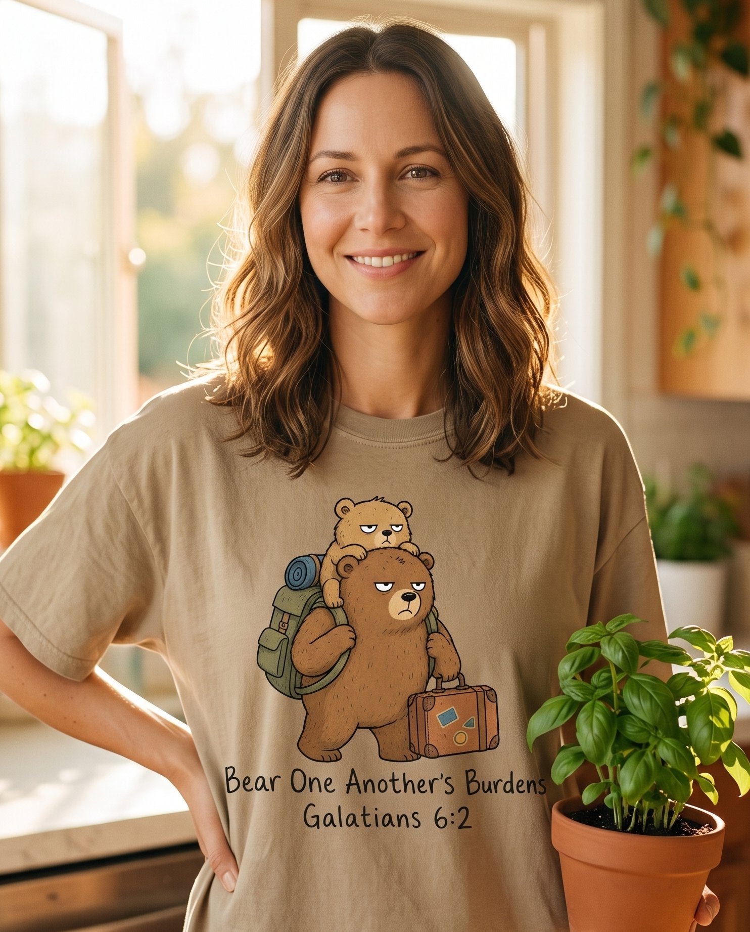 Bear One Another's Burdens – Khaki women's Christian tee, lifestyle photo in morning kitchen setting – Tired grumpy bear carrying a smaller bear on its back along with a bac – Galatians 6:2 – She Wears Faith