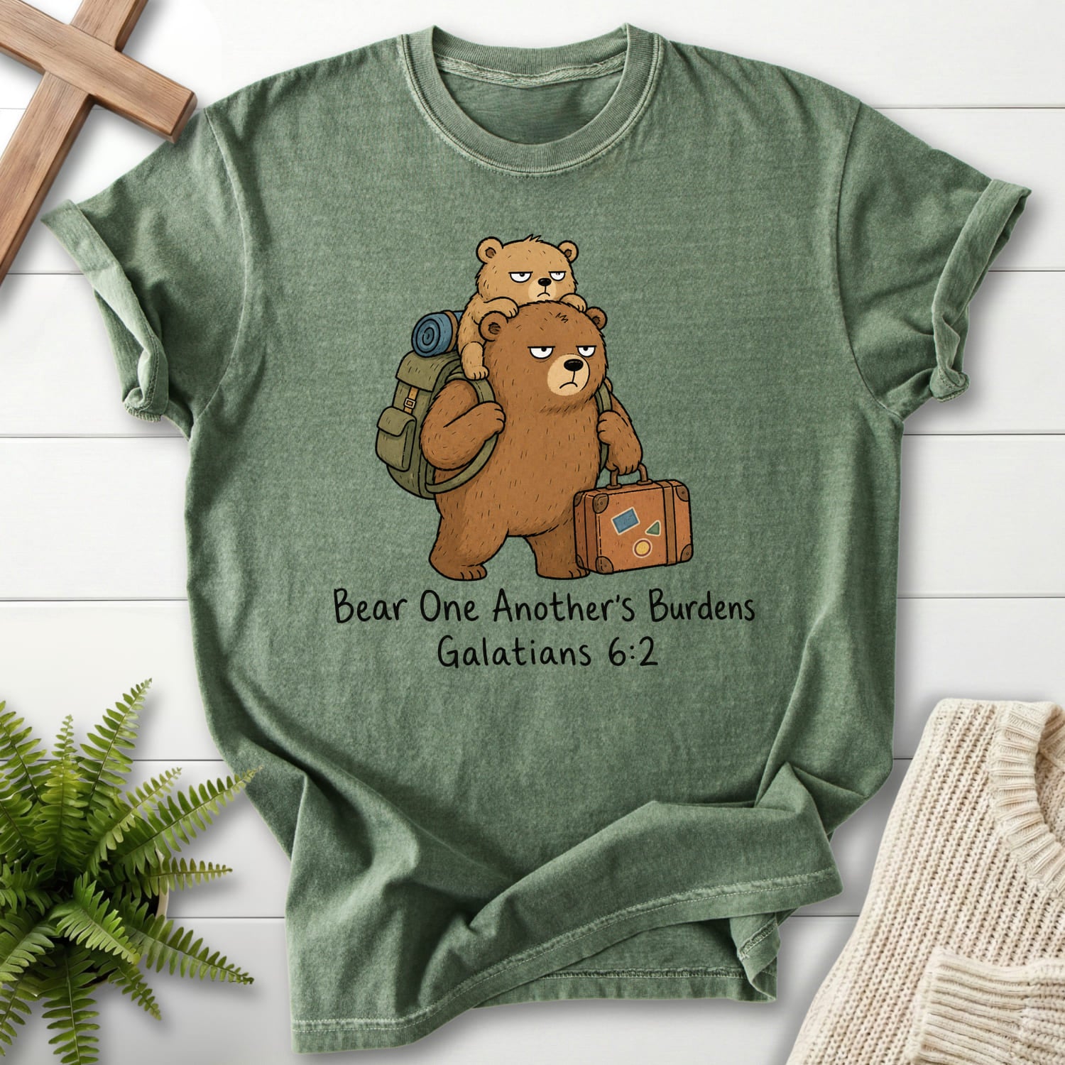 Flat lay of a Moss Comfort Colors 1717 Scripture shirt featuring "Bear One Another's Burdens T-Shirt" Galatians 6:2.