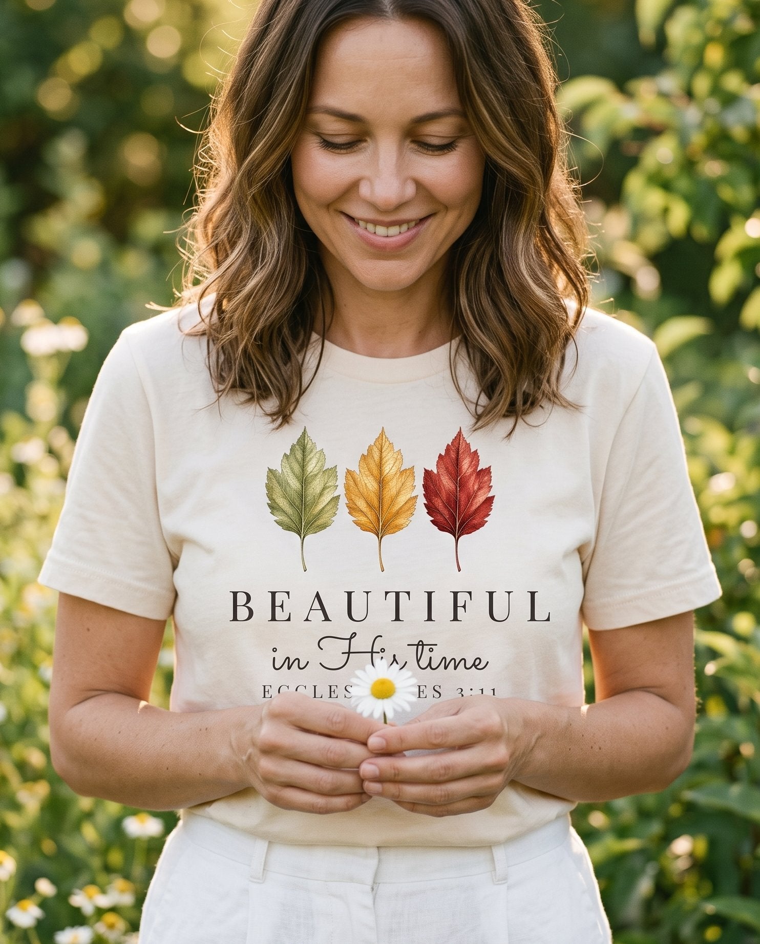 Beautiful in His Time Faith – Ivory women's Christian tee, lifestyle photo in outdoor garden – Three autumn leaves in green – Ecclesiastes 3:11 – She Wears Faith
