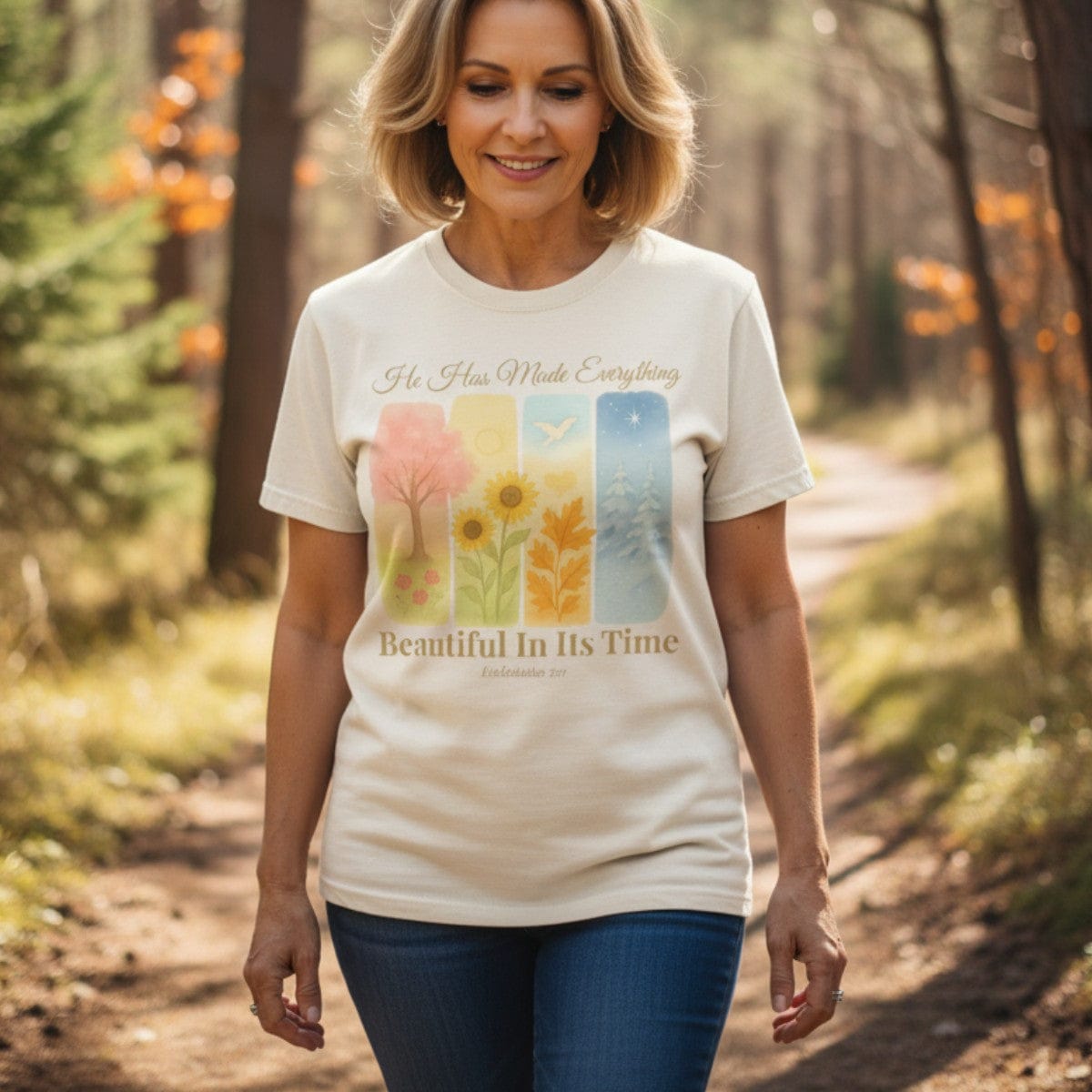 Smiling woman walking through a forest wearing a Comfort Colors 1717 ivory “He Has Made Everything Beautiful in Its Time – Ecclesiastes 3:11” t-shirt. A peaceful and elegant faith-based apparel for women and meaningful Christian mom gift idea.