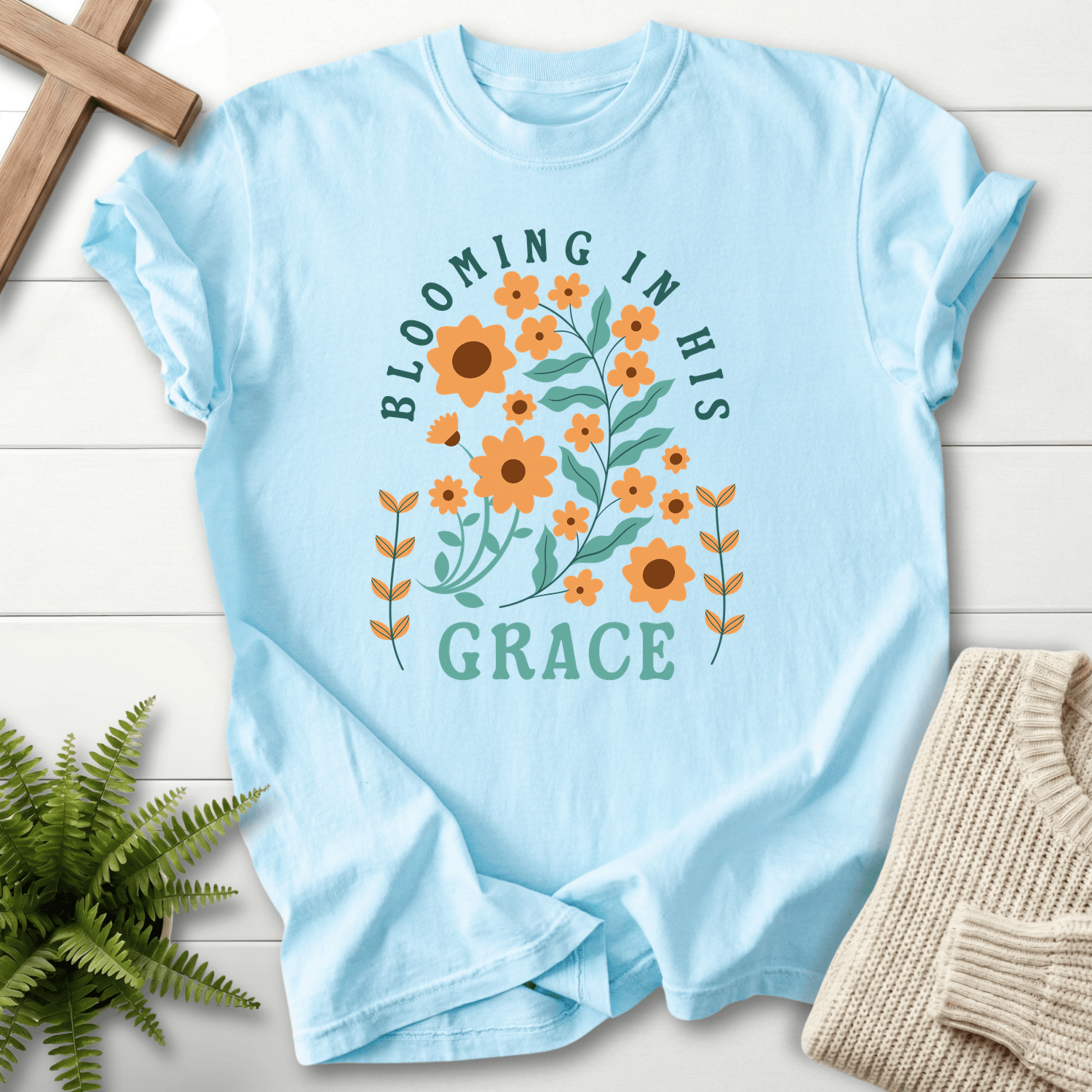 Chambray Christian t-shirt for women with a retro sunflower design and teal block lettering, She Wears Faith.
