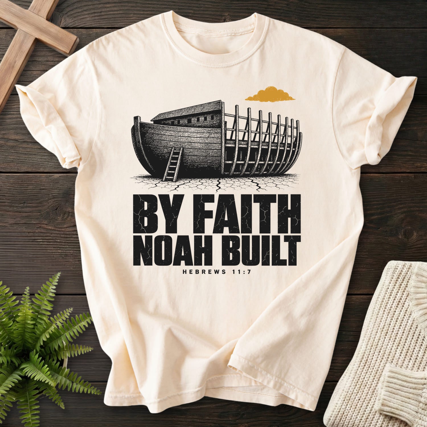 Flat lay of an Ivory Comfort Colors 1717 women's Christian tee featuring "By Faith Noah Built Hebrews 11 7 T-Shirt" Hebrews 11:7.