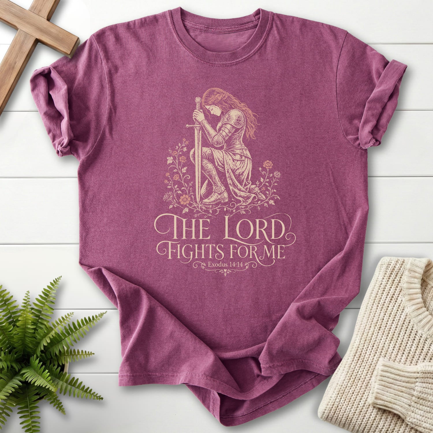 Flat lay of a Berry Scripture shirt featuring floral line art with "The LORD Fights For Me T-Shirt" Exodus 14:14.