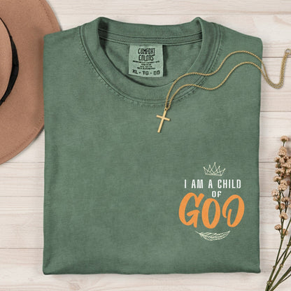 Flatlay of a Comfort Colors 1717 moss “I Am a Child of God” t-shirt featuring elegant crown and feather artwork. A soft women’s scripture tee — meaningful faith-based apparel for women and lovely modern Christian shirt, perfect for Christian mom gift ideas.