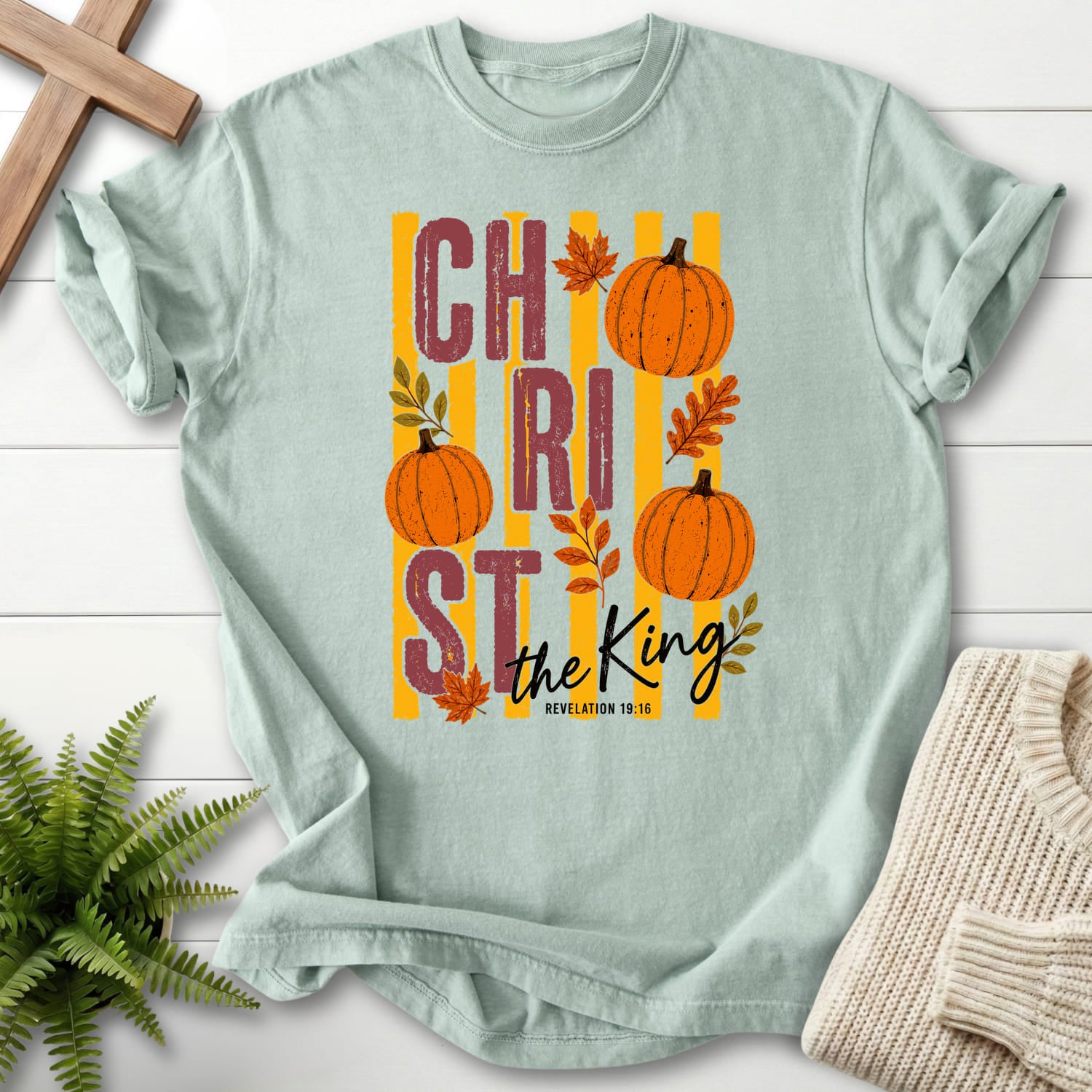 Flat lay of a Bay women's Christian tee featuring script typography with "Christ The King Fall T-Shirt" Revelation 1:16.