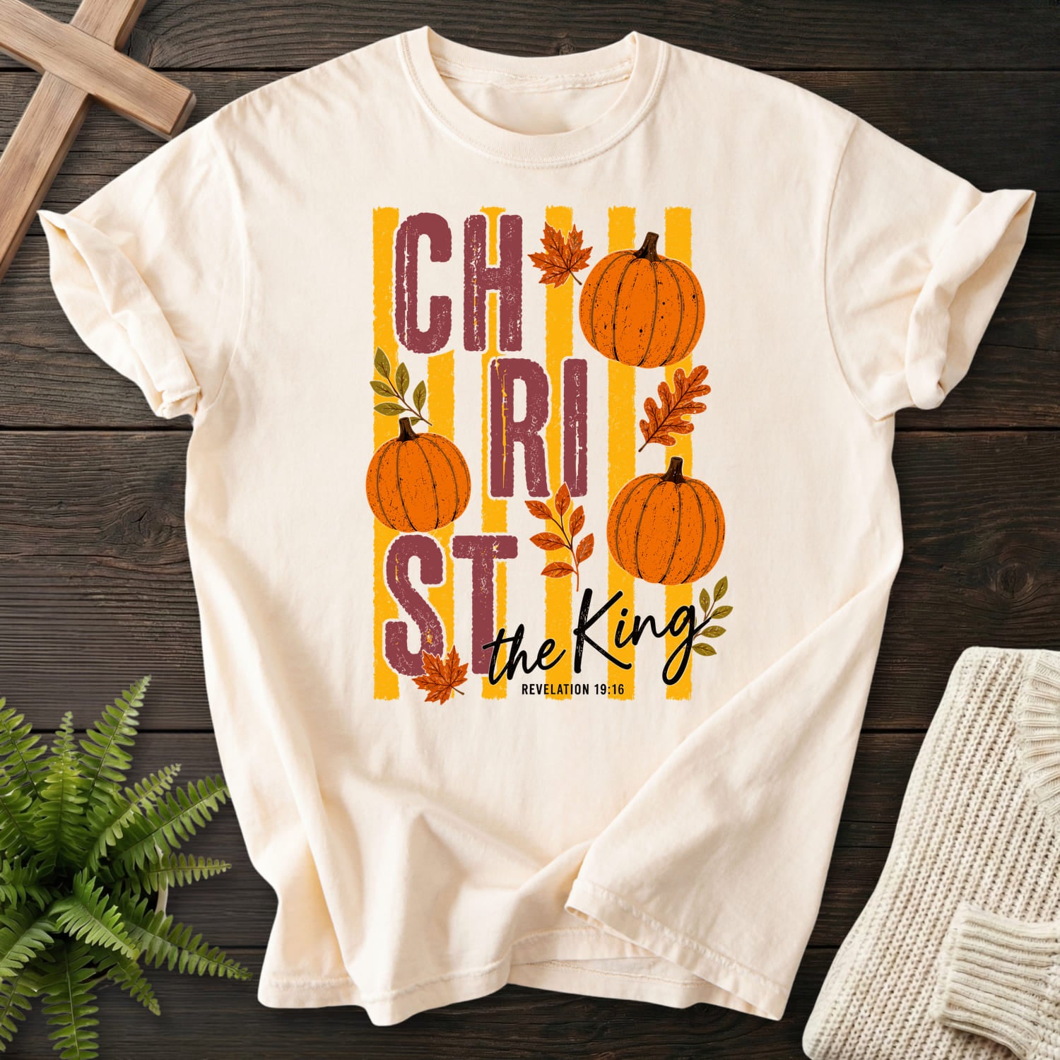 Flatlay of an Ivory faith-based tee with script typography with "Christ The King Fall T-Shirt" Revelation 1:16.