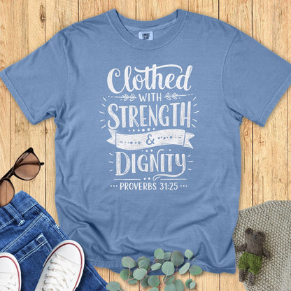 Comfort Colors 1717 blue jean “Clothed with Strength & Dignity – Proverbs 31:25” t-shirt with vintage-inspired lettering and banner detail. A stylish modern Christian shirt — perfect women’s scripture tee and heartfelt Christian mom gift idea.