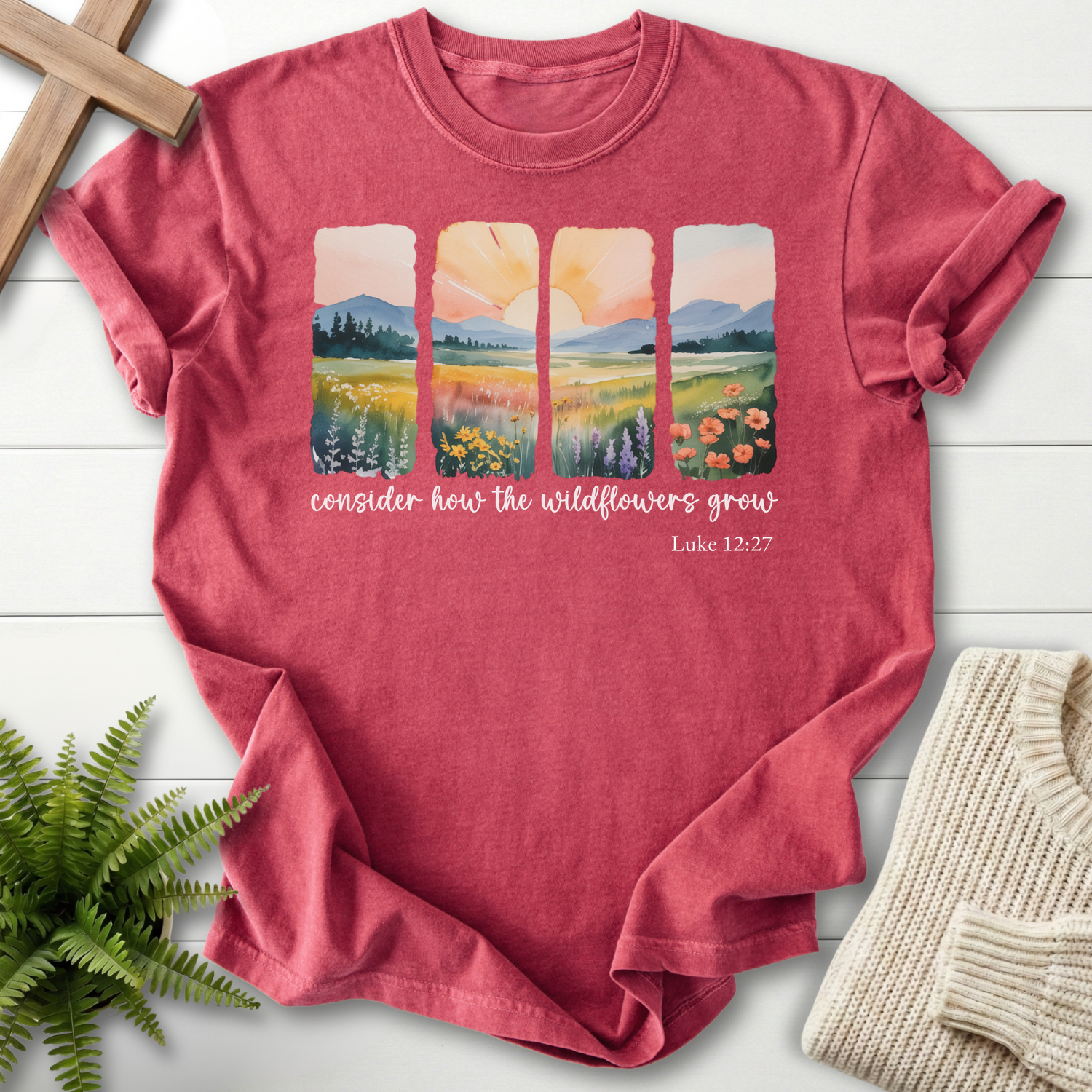 Crimson Christian t-shirt for women with watercolor wildflower and mountain landscape panels, inspired by Luke 12:27.