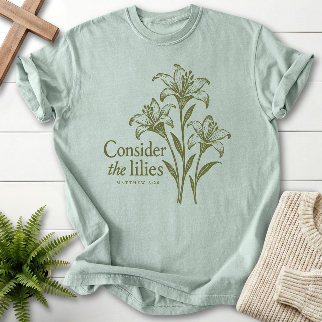 Flat lay of a Bay Scripture shirt featuring "Consider the Lilies Botanical T-Shirt" Matthew 6:28.