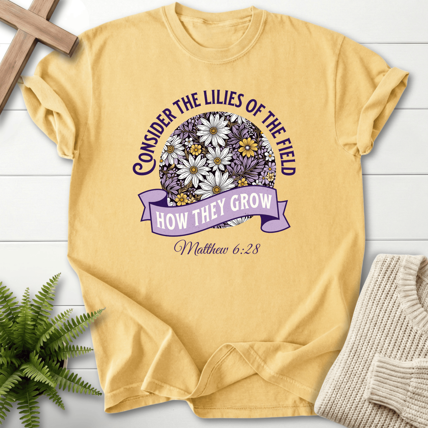 Butter yellow women's faith t-shirt with a circular purple and white floral design, Comfort Colors 1717, inspired by Matthew 6:28.