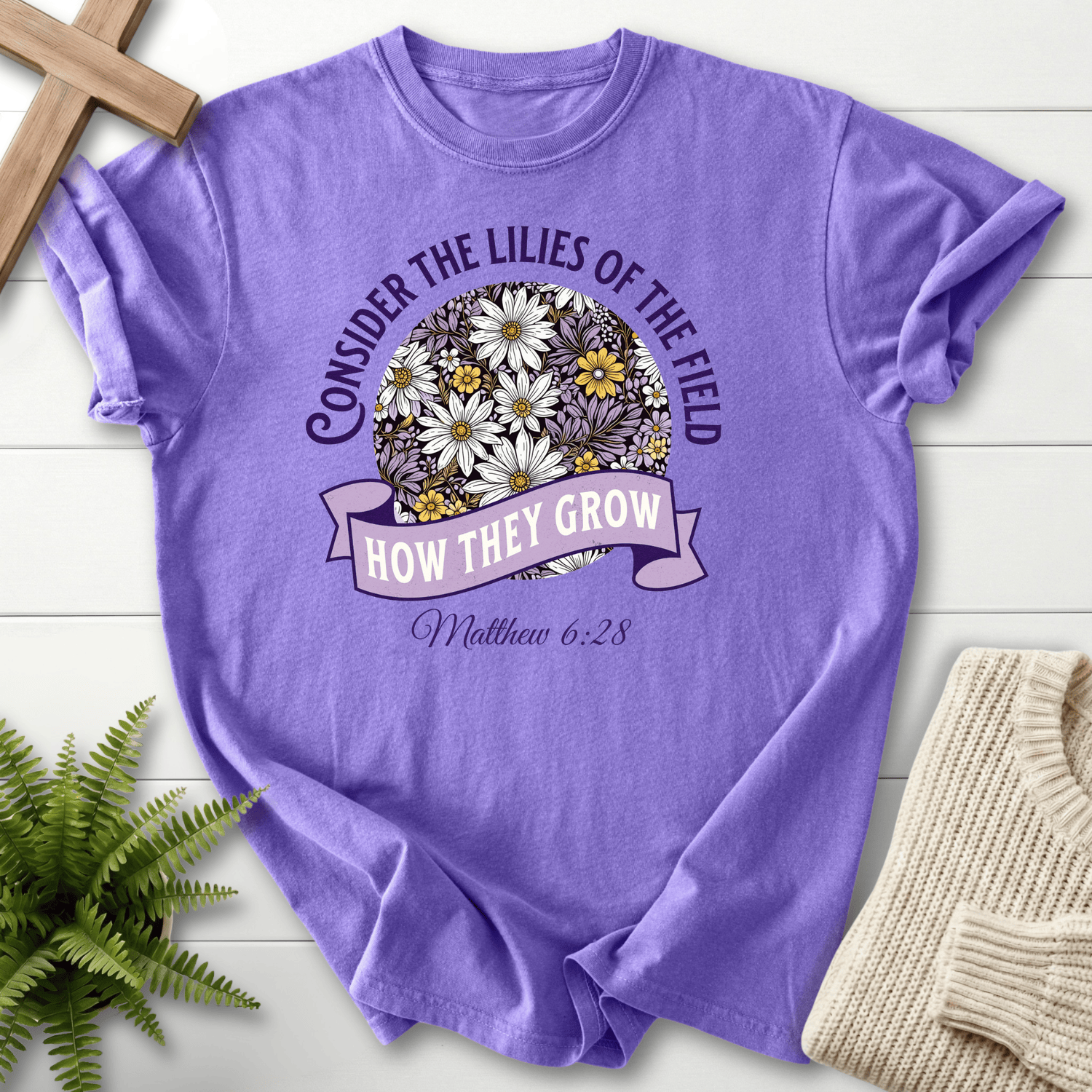 Violet Christian t-shirt for women with a purple floral sphere and banner ribbon design, inspired by Matthew 6:28.