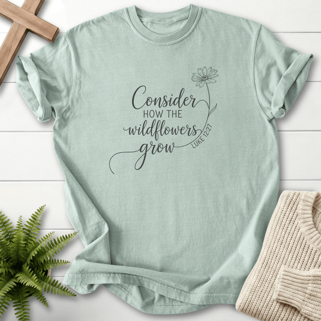 Bay Christian t-shirt for women with black ink line art and a single daisy, inspired by Luke 12:27.