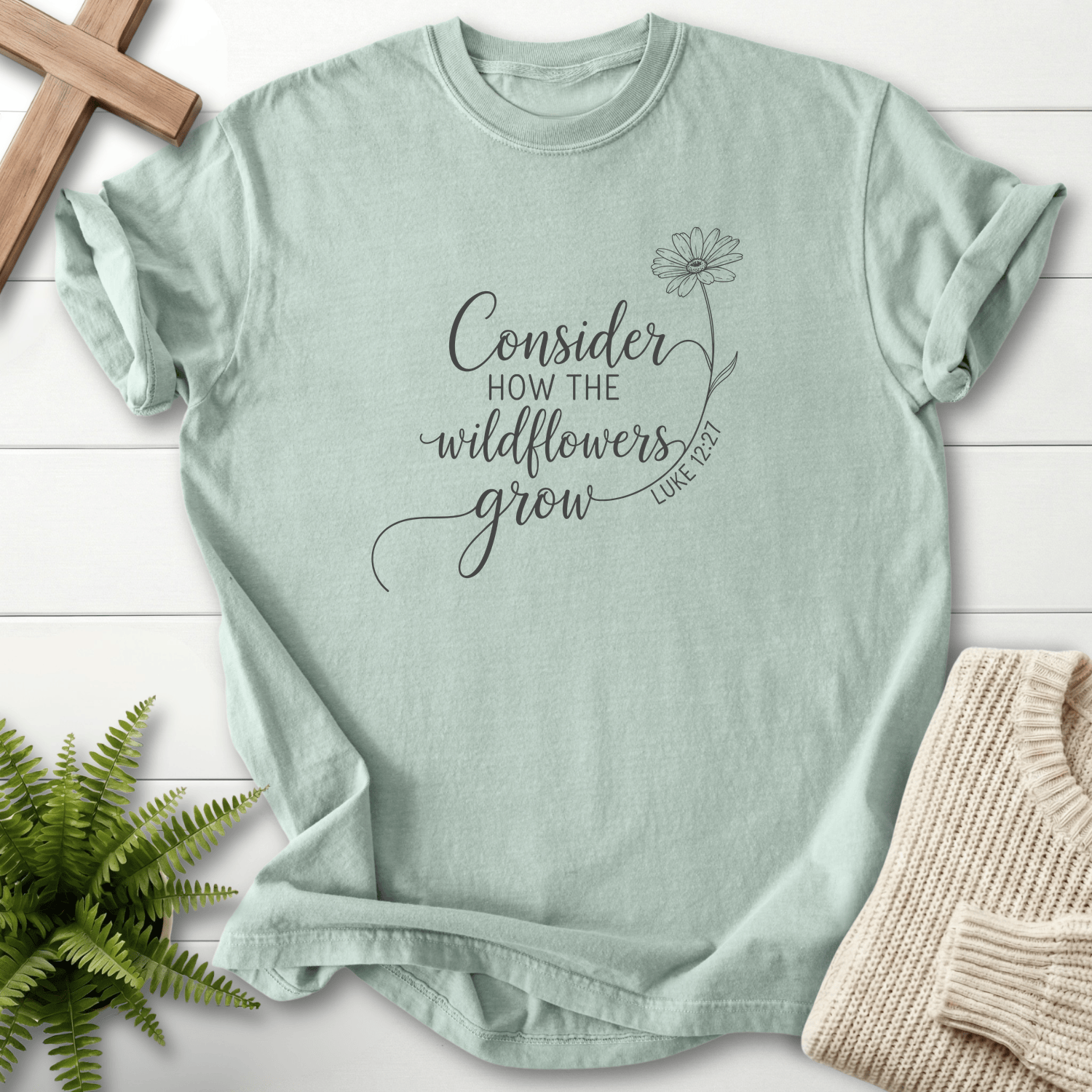 Bay Christian t-shirt for women with black ink line art and a single daisy, inspired by Luke 12:27.