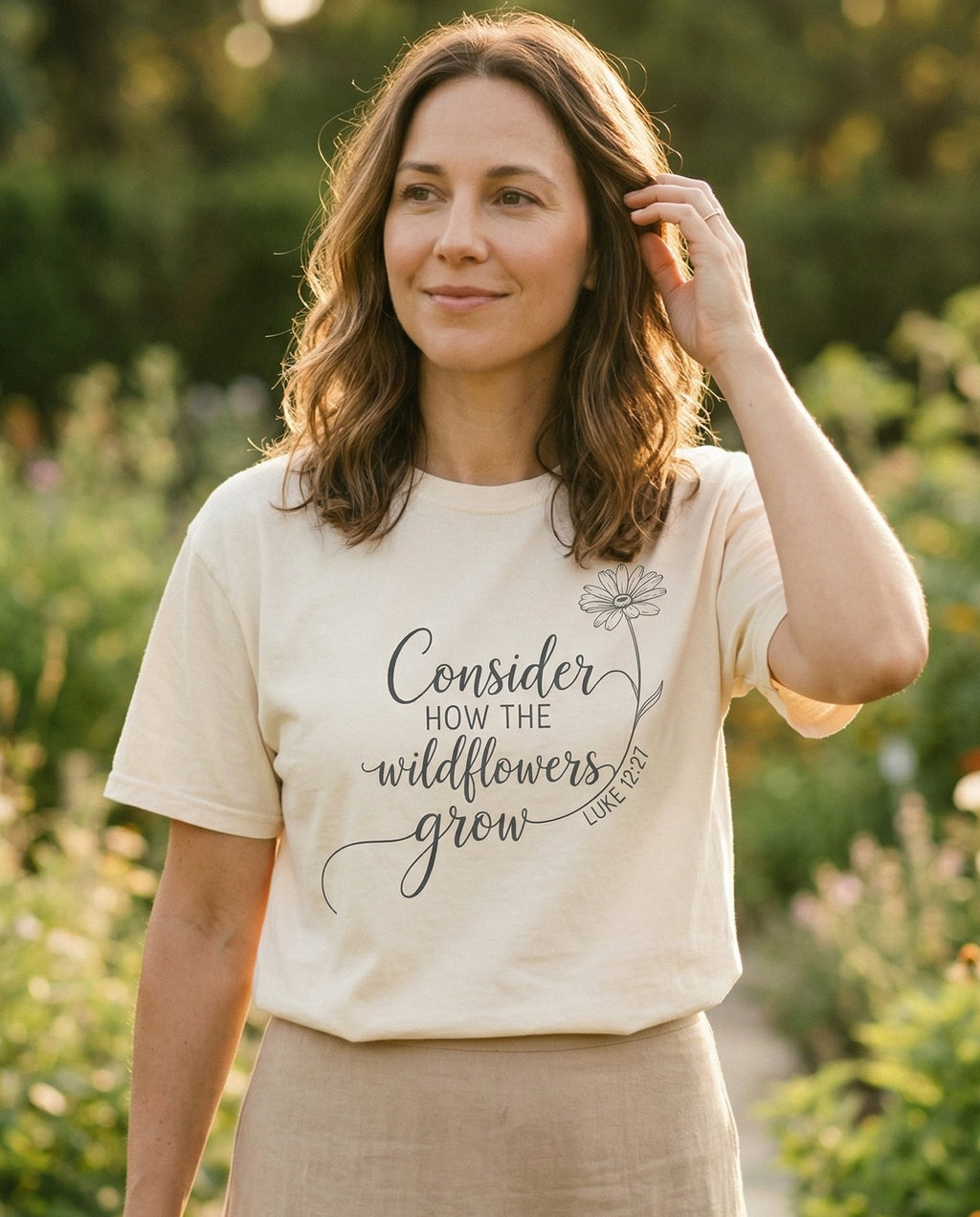 Consider the Wildflowers Line art – Ivory women's Christian tee, lifestyle photo in outdoor garden – Delicate line art script 'Consider how the wildflowers grow – Luke 12:27 – She Wears Faith