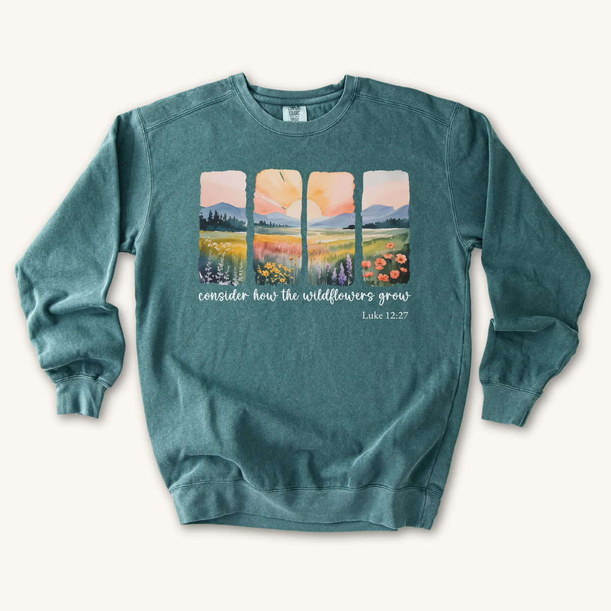 Blue Spruce Christian sweatshirt with four painted panels of sunrise over hills and a wildflower meadow, reading consider how the wildflowers grow, Luke 12:27