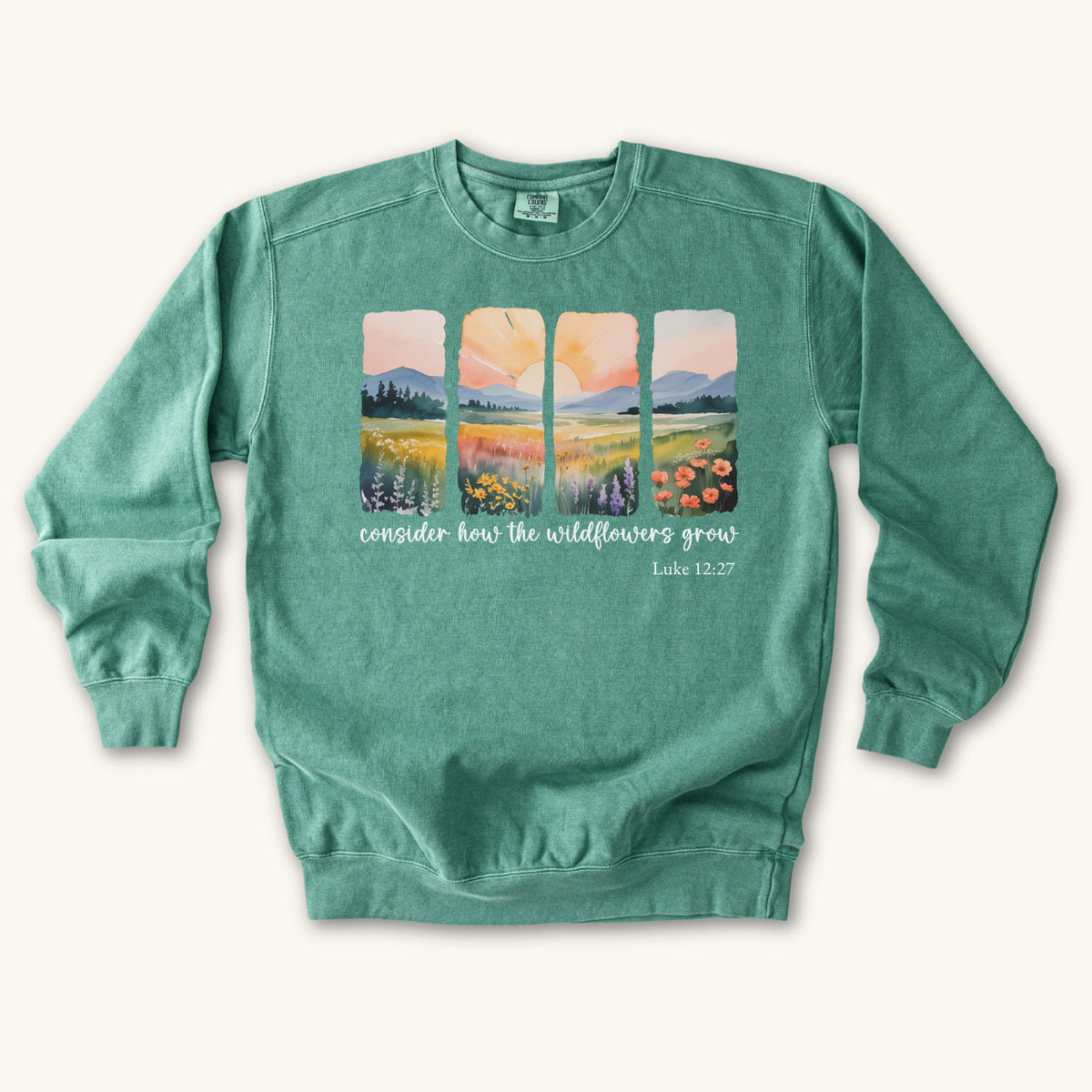 Light Green Christian sweatshirt with four painted panels of sunrise over hills and a wildflower meadow, reading consider how the wildflowers grow, Luke 12:27