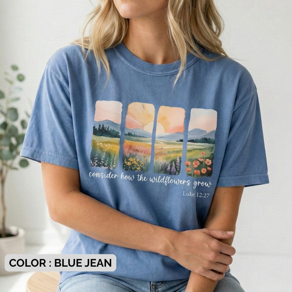 Blue jean Bible Verse Shirt featuring four vertical watercolor panels depicting a sunrise over a field of flowers, with the text "consider how the wildflowers grow" and "Luke 12:27" printed in white.