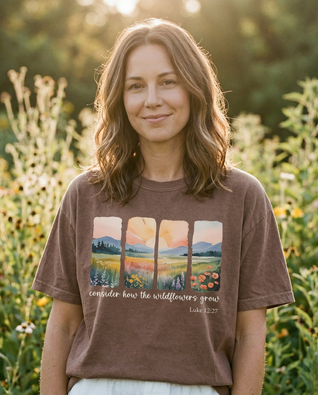 Consider the Wildflowers Watercolors – Espresso women's Christian tee, lifestyle photo in outdoor garden – Four watercolor landscape panels showing wildflower meadows with mount – Luke 12:27 – She Wears Faith