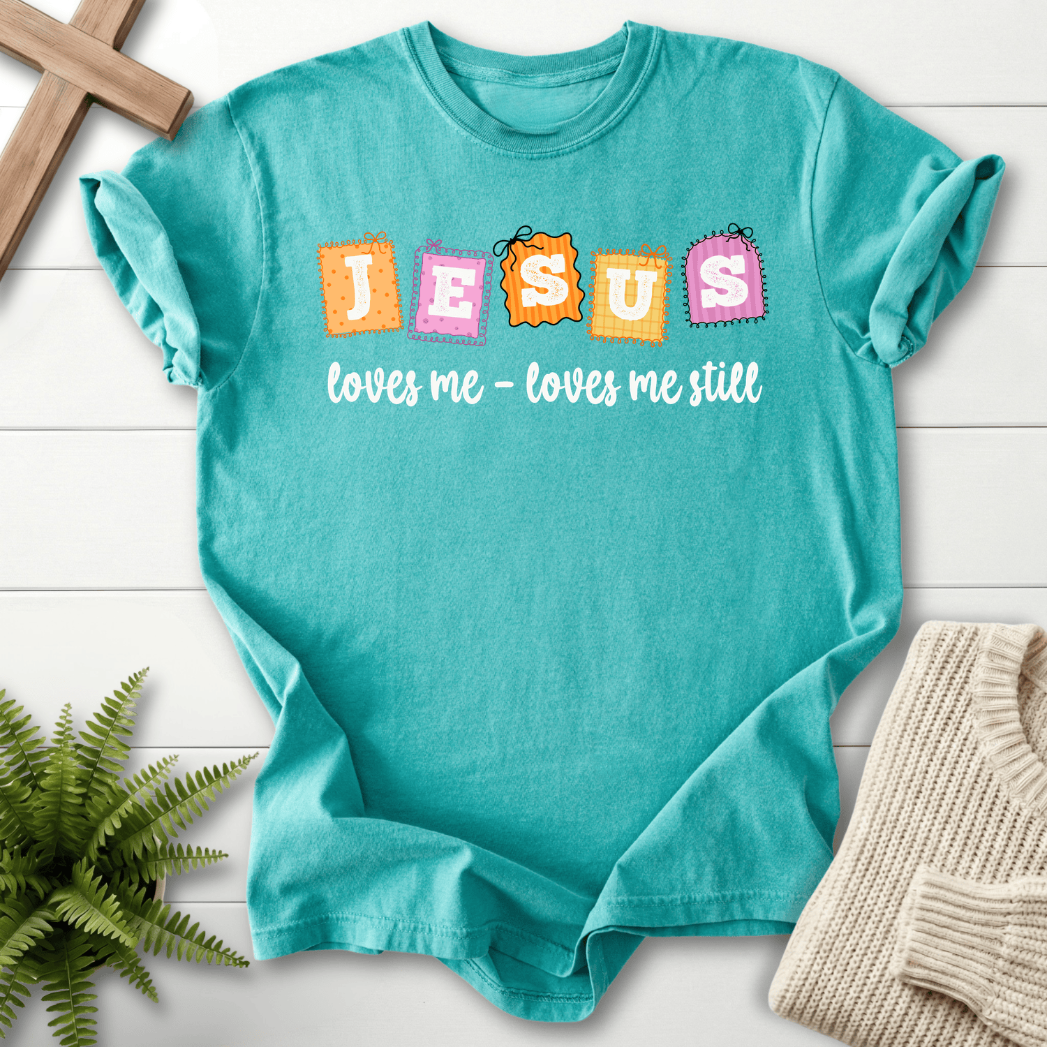 Seafoam women's Christian t-shirt with colorful "JESUS loves me loves me still" patchwork design