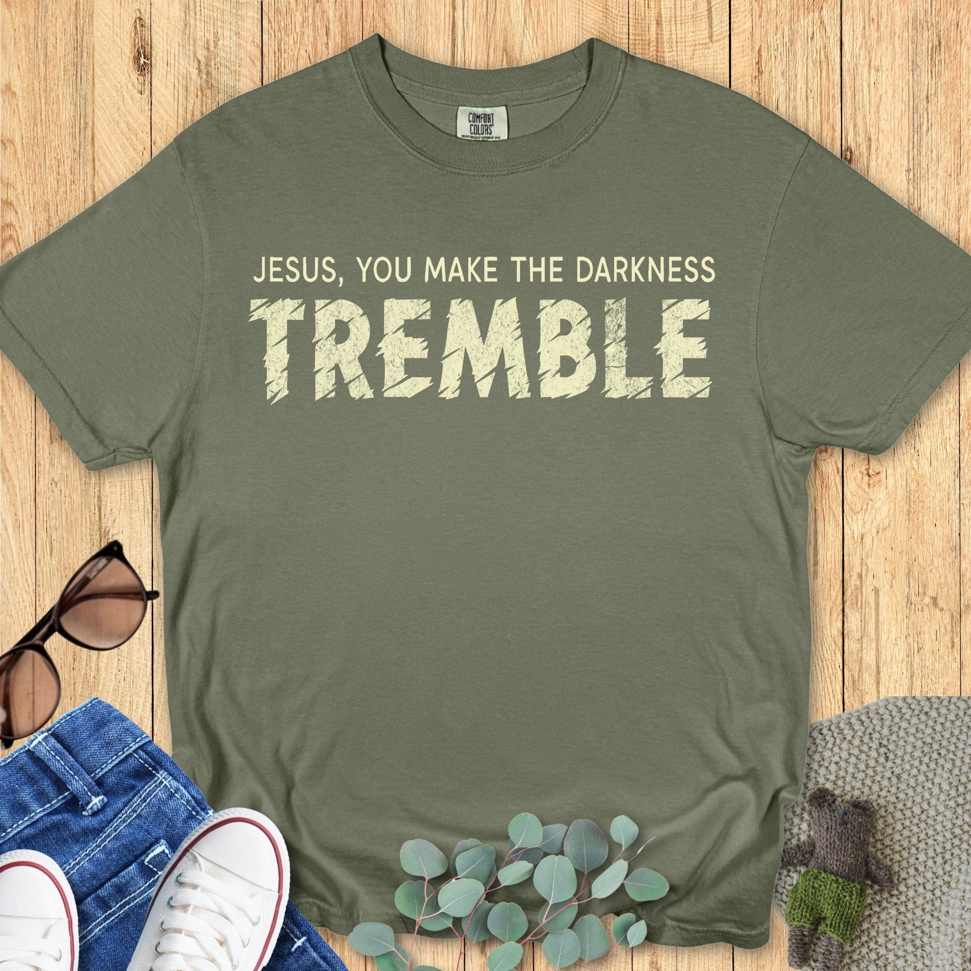 Flatlay of a Comfort Colors 1717 sage “Jesus, You Make the Darkness Tremble” t-shirt with bold distressed text. A faith-filled women’s scripture tee — classic faith-based apparel for women and powerful modern Christian shirt, thoughtful Christian mom gift idea.