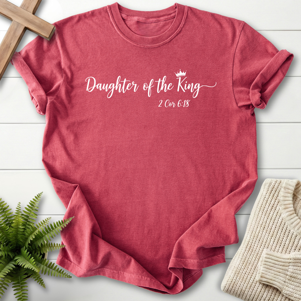 Crimson women's faith t-shirt with elegant white cursive 'Daughter of the King' lettering and a crown icon, inspired by 2 Corinthians 6:18.