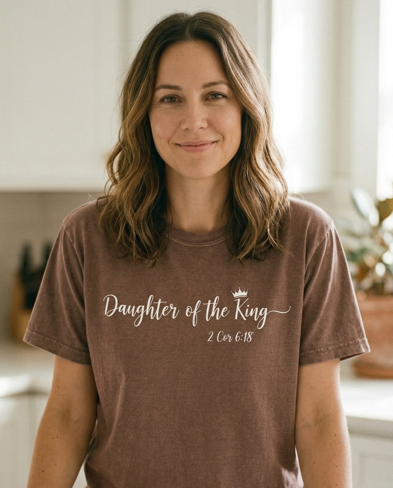 Daughter of the King – Espresso women's Christian tee, lifestyle photo in morning kitchen setting – Elegant cursive script 'Daughter of the King' with a small crown icon  – 2 Corinthians 6:18 – She Wears Faith