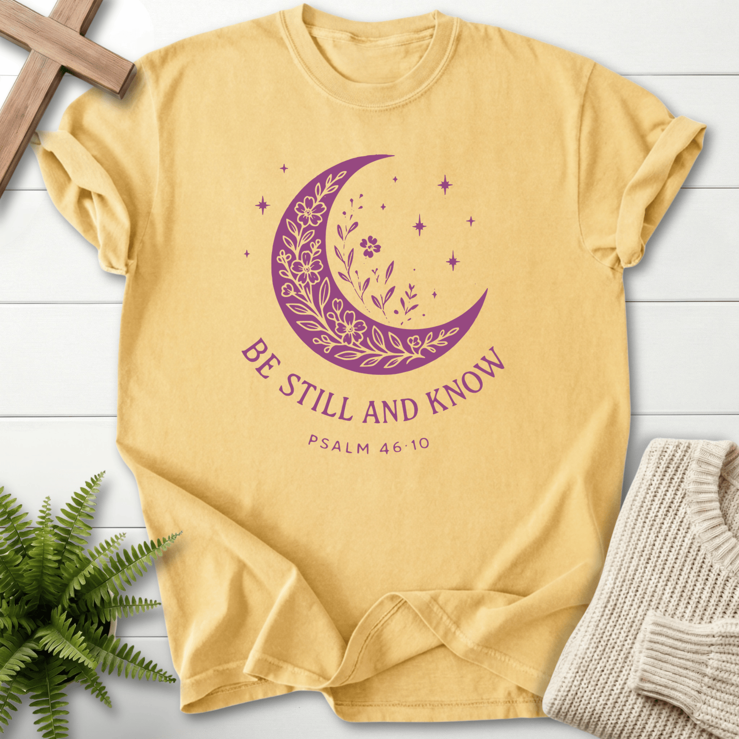 Butter yellow Scripture shirt for women with a purple crescent moon, wildflowers, and 'Be Still and Know', by She Wears Faith.