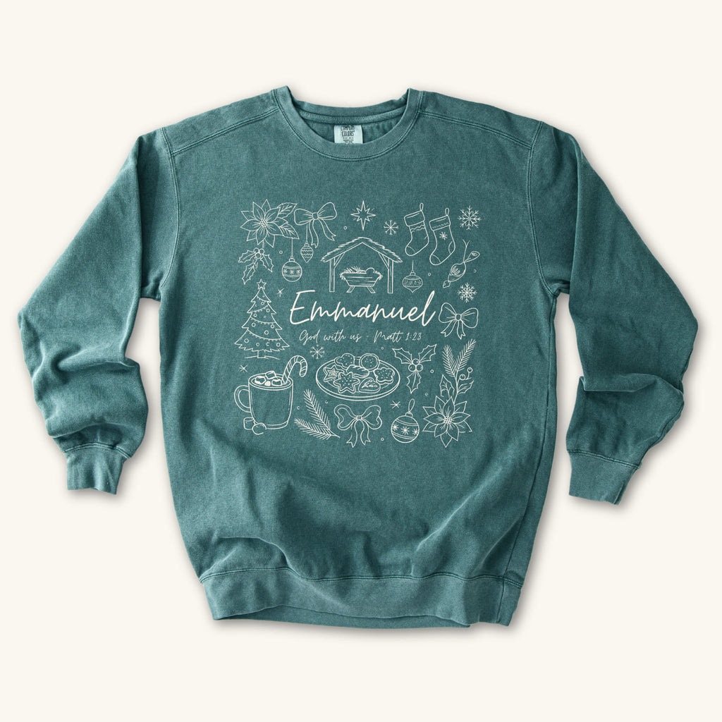 Blue Spruce Christian Christmas sweatshirt with Emmanuel God with us script and Matthew 1:23 surrounded by doodles of a manger, stockings, a tree, cocoa and cookies.