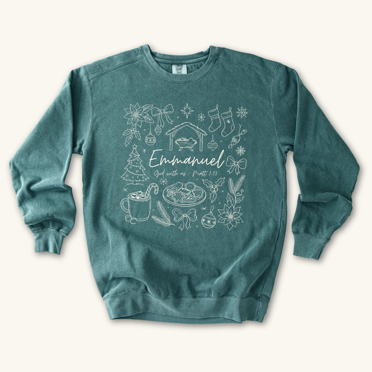 Blue Spruce Christian Christmas sweatshirt with Emmanuel God with us script and Matthew 1:23 surrounded by doodles of a manger, stockings, a tree, cocoa and cookies.