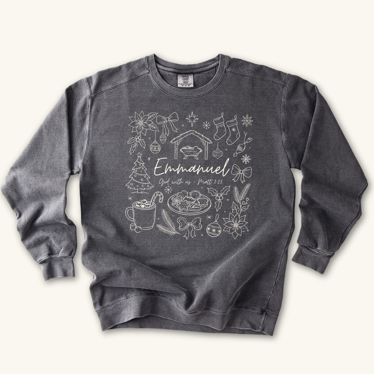 Pepper Christian Christmas sweatshirt with Emmanuel God with us script and Matthew 1:23 surrounded by doodles of a manger, stockings, a tree, cocoa and cookies.