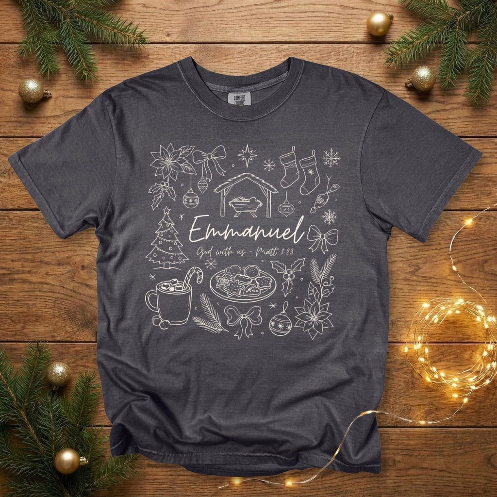 Comfort Colors 1717 pepper grey Christian women’s T-shirt with a detailed Christmas doodle-style illustration including the nativity, poinsettias, stockings, ornaments, Christmas tree, and “Emmanuel – God with us, Matt 1:23.” A vintage-style scripture-based US faith wear tee for the holiday season.