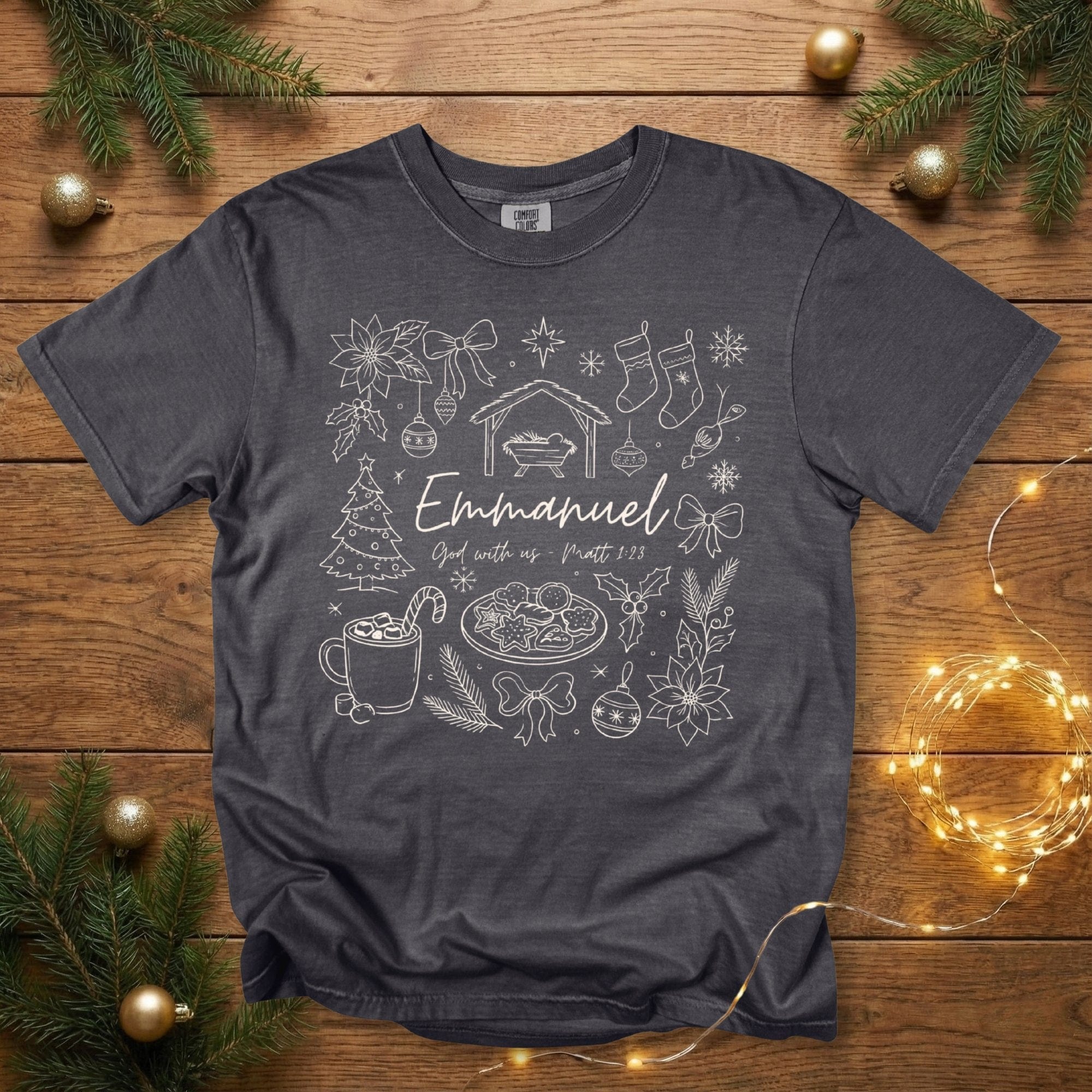 Comfort Colors 1717 pepper grey Christian women’s T-shirt with a detailed Christmas doodle-style illustration including the nativity, poinsettias, stockings, ornaments, Christmas tree, and “Emmanuel – God with us, Matt 1:23.” A vintage-style scripture-based US faith wear tee for the holiday season.