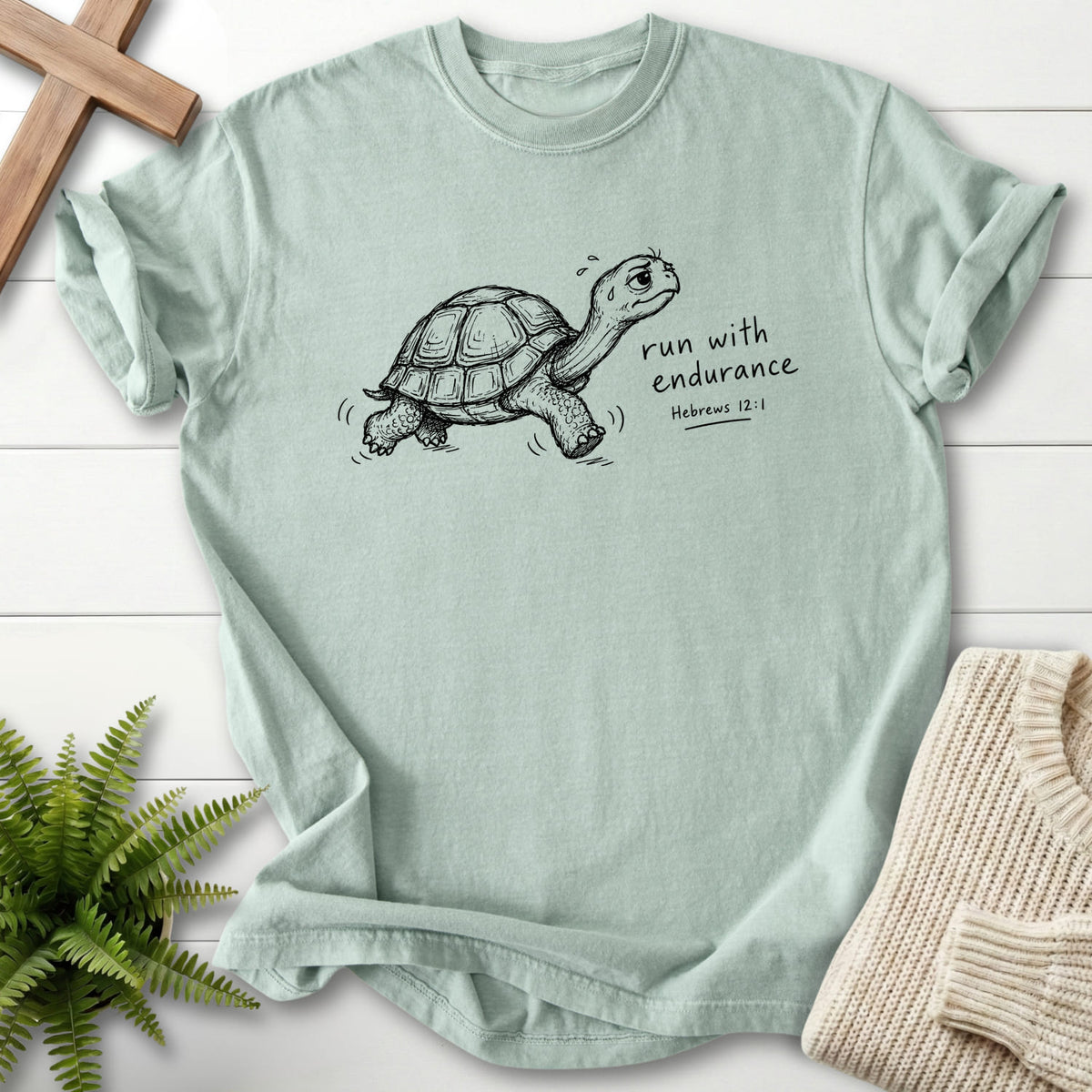 Flat lay of a Bay Bible verse tee featuring "Endurance Turtle Hebrews 12:1 T-Shirt" Hebrews 12:1.