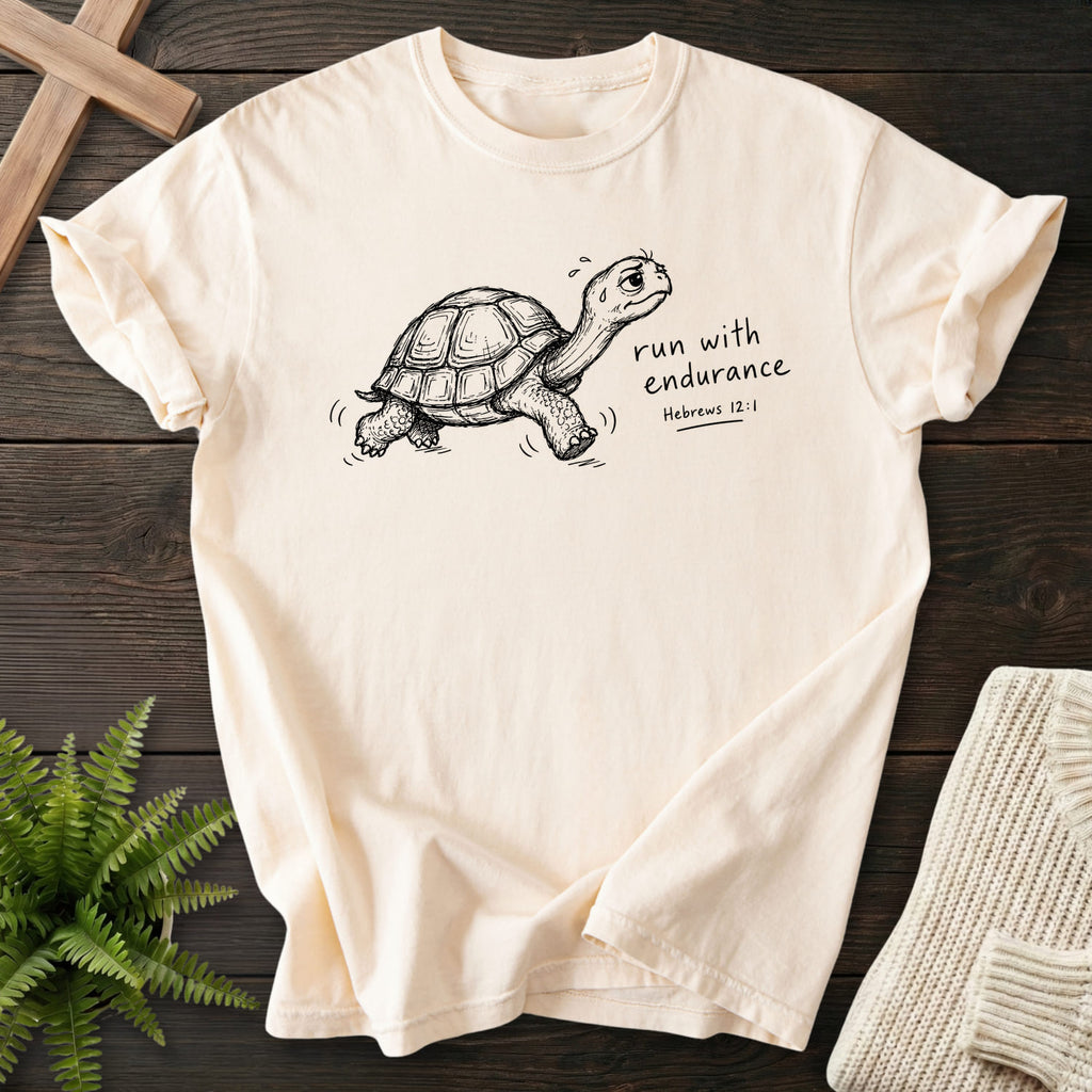 Flatlay of an Ivory women's Christian tee with "Endurance Turtle Hebrews 12:1 T-Shirt" Hebrews 12:1.