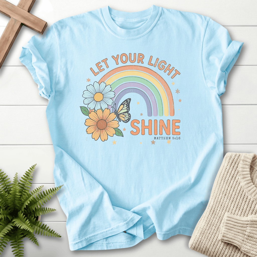 Chambray women's Bible verse tee with pastel rainbow, daisy, and butterfly motif, inspired by Matthew 5:16.