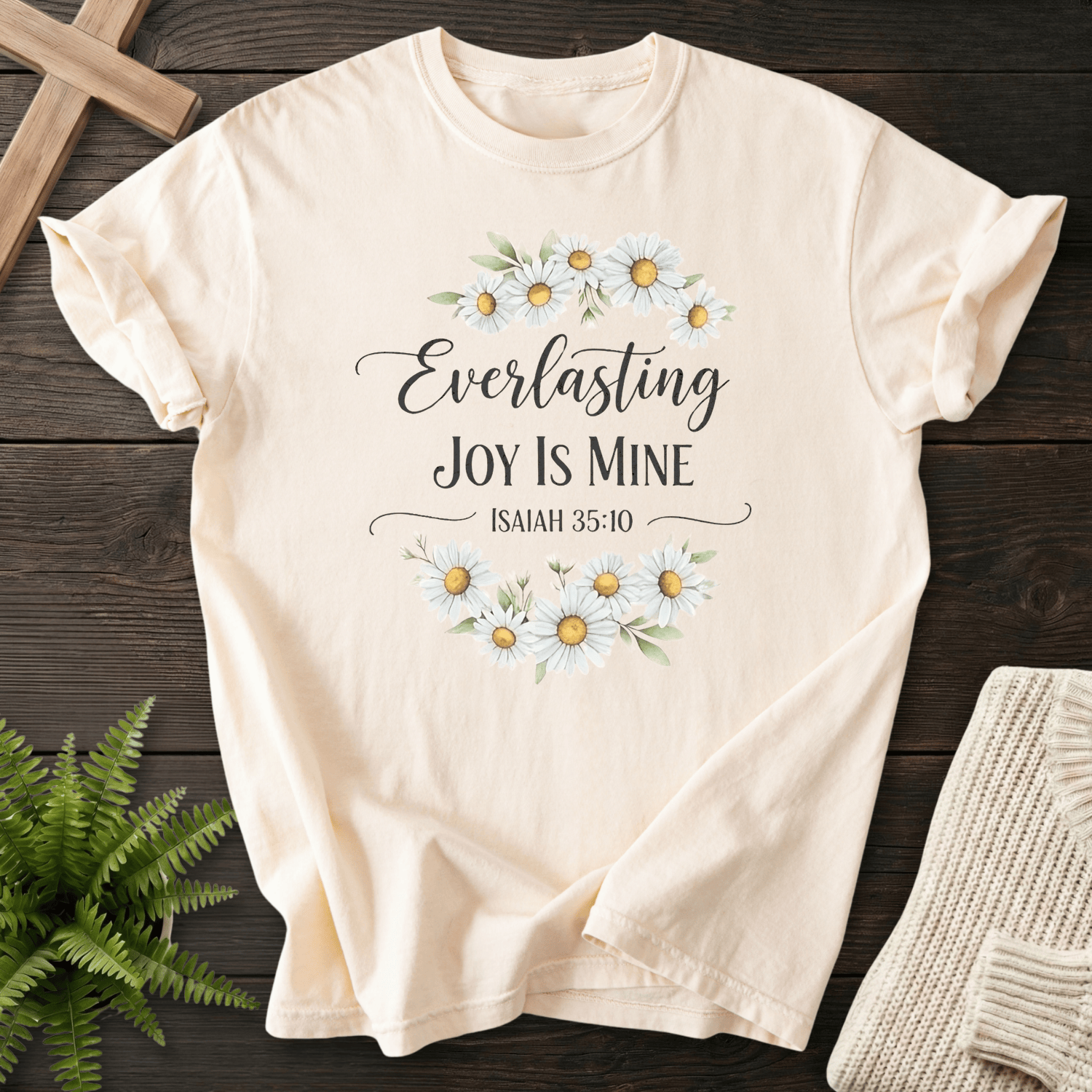Ivory women's faith t-shirt with a white daisy wreath and elegant script lettering, inspired by Isaiah 35:10.