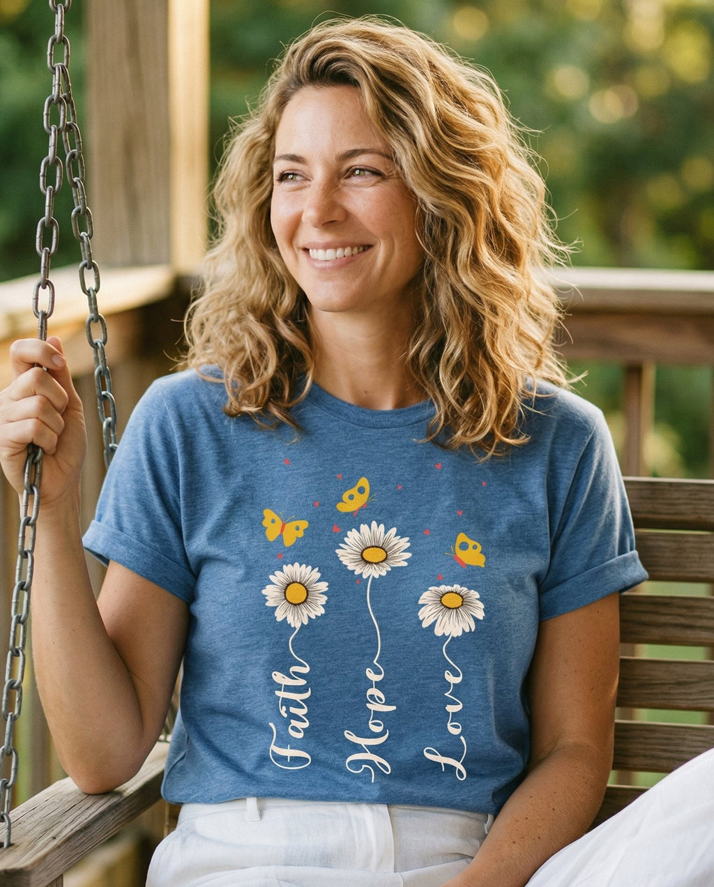 Faith, Hope, Love – Blue Jean women's Christian tee, lifestyle photo in sunny porch – Three white daisies with their stems forming the words 'Faith' – She Wears Faith