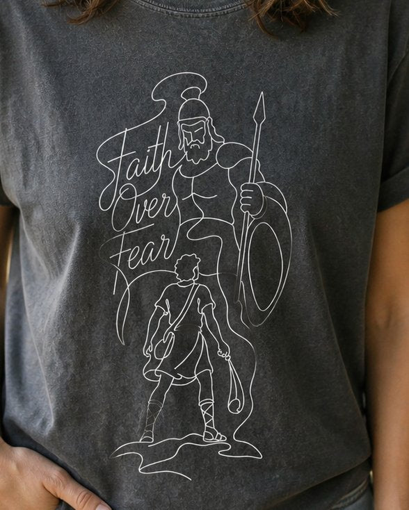 Faith Over Fear David vs Goliath - Pepper women's Christian tee, lifestyle photo in nature trail - Single-line art of David facing the giant Goliath - 1 Samuel 17 - She Wears Faith