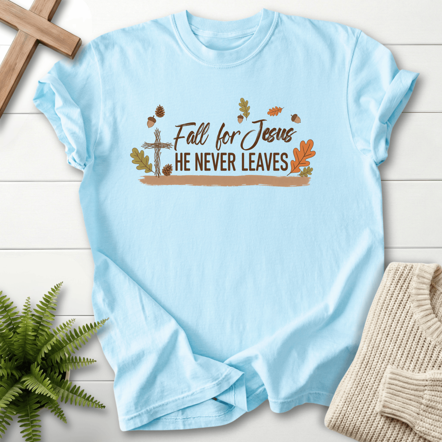 Chambray women's faith t-shirt with a rustic cross and autumn leaf design around 'Fall for Jesus He Never Leaves'.