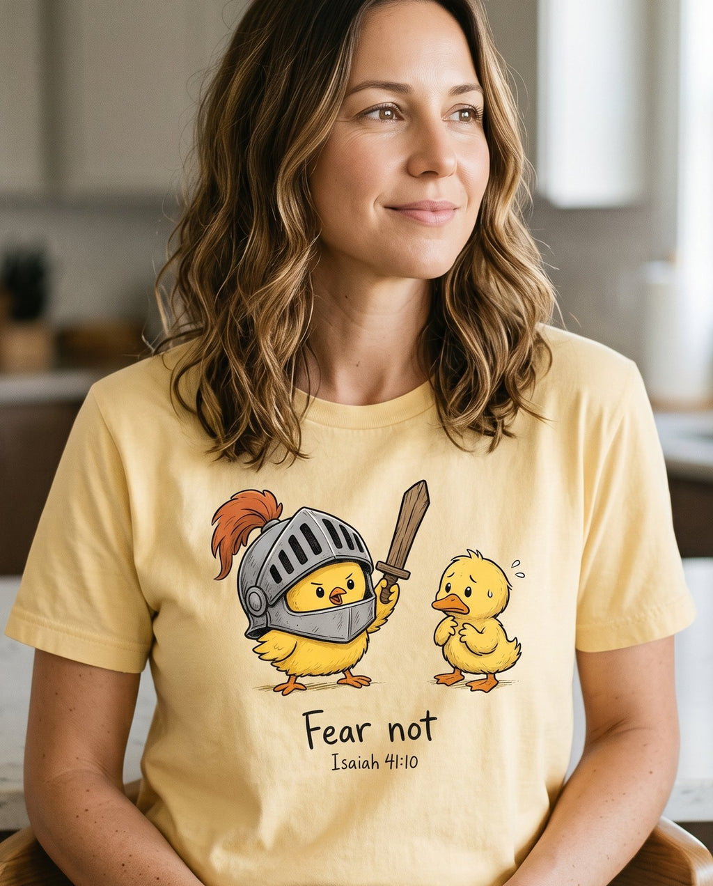 Fear Not Isaiah 41 10 Chick – Butter women's Christian tee, lifestyle photo in morning kitchen setting – Brave little chick in a knight's helmet brandishing a wooden sword to  – Isaiah 41:10 – She Wears Faith