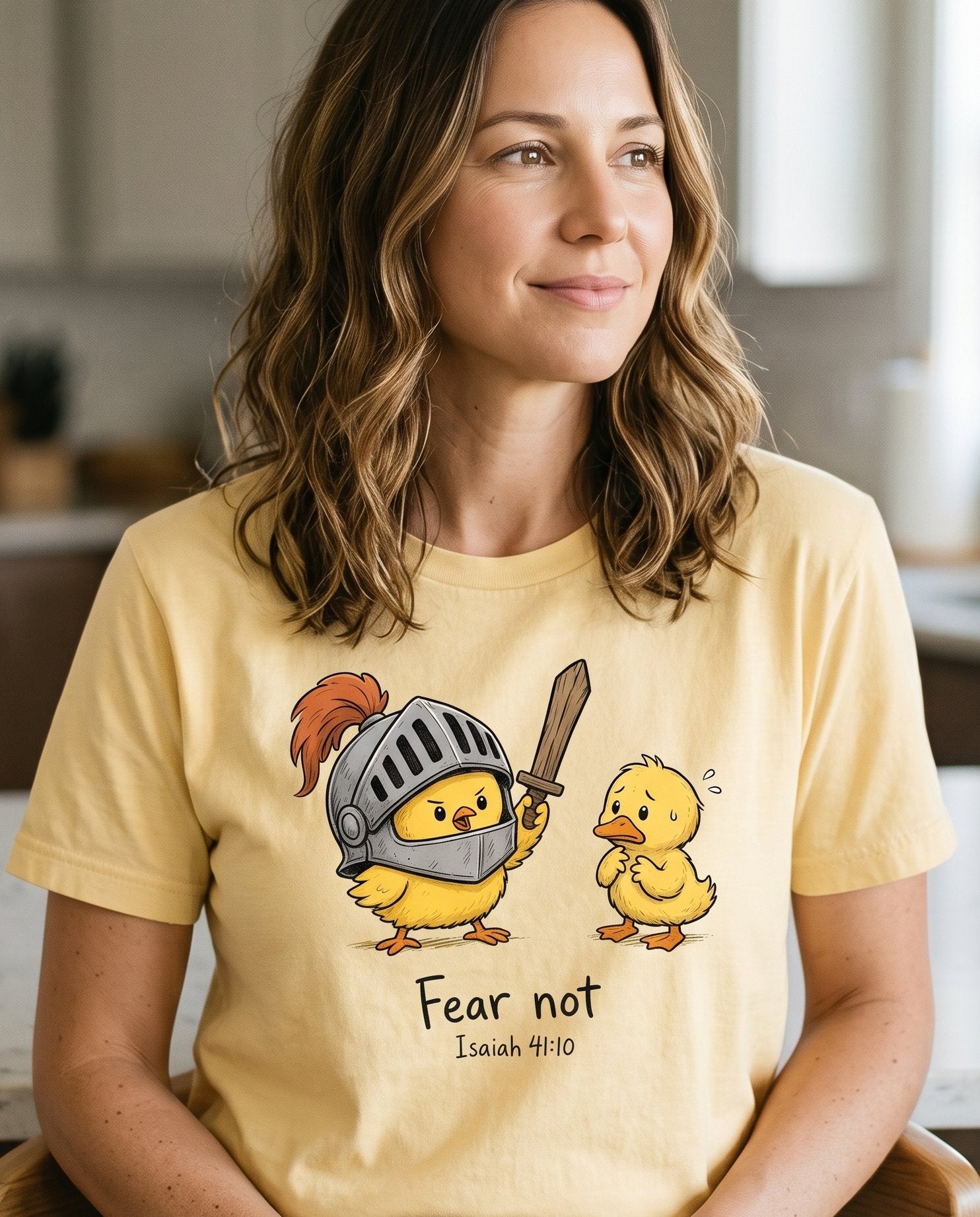 Fear Not Isaiah 41 10 Chick – Butter women's Christian tee, lifestyle photo in morning kitchen setting – Brave little chick in a knight's helmet brandishing a wooden sword to  – Isaiah 41:10 – She Wears Faith