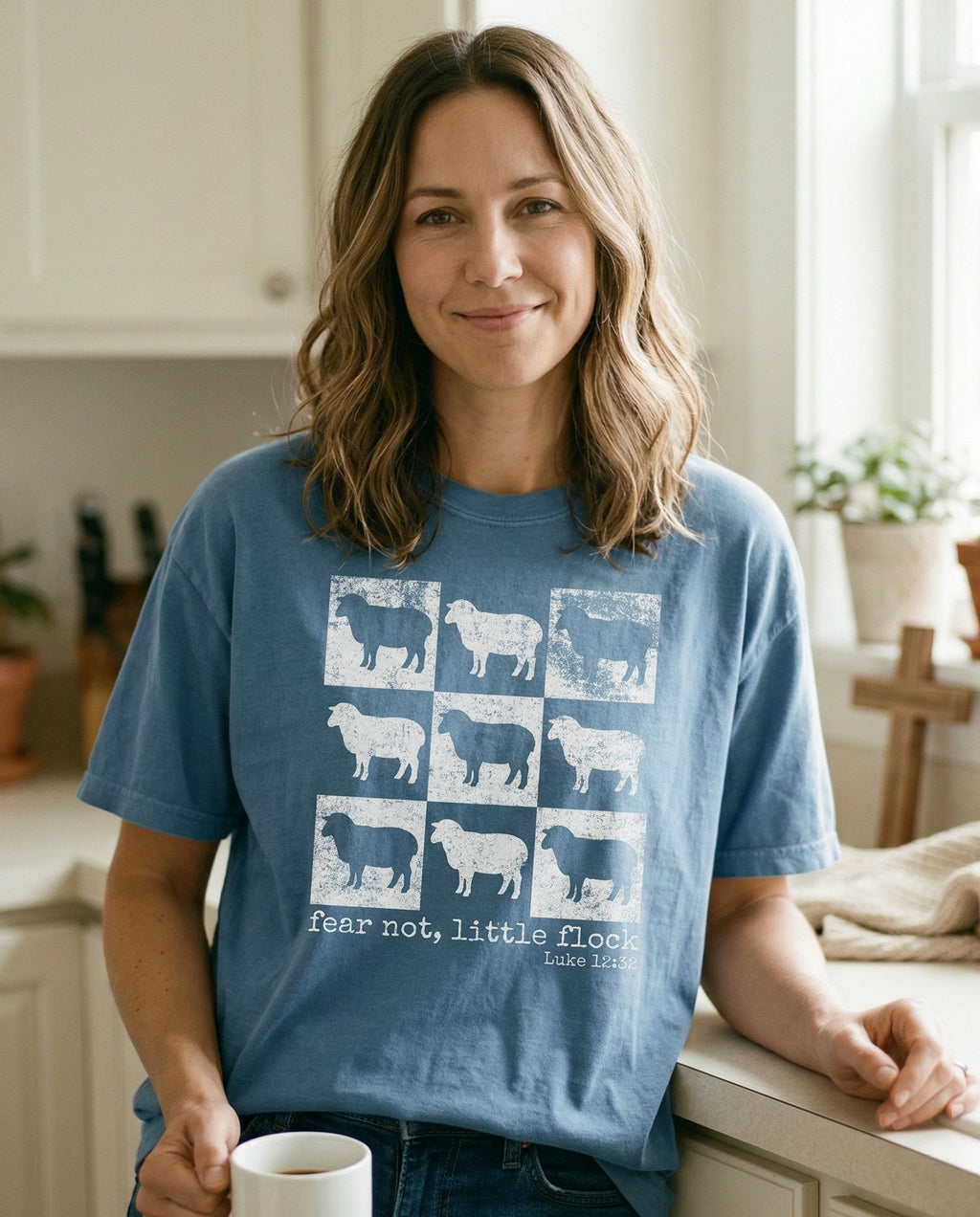 Fear Not, Little Flock – Blue Jean women's Christian tee, lifestyle photo in morning kitchen setting – Vintage-style 3x3 grid of distressed sheep silhouette illustrations in – Luke 12:32 – She Wears Faith
