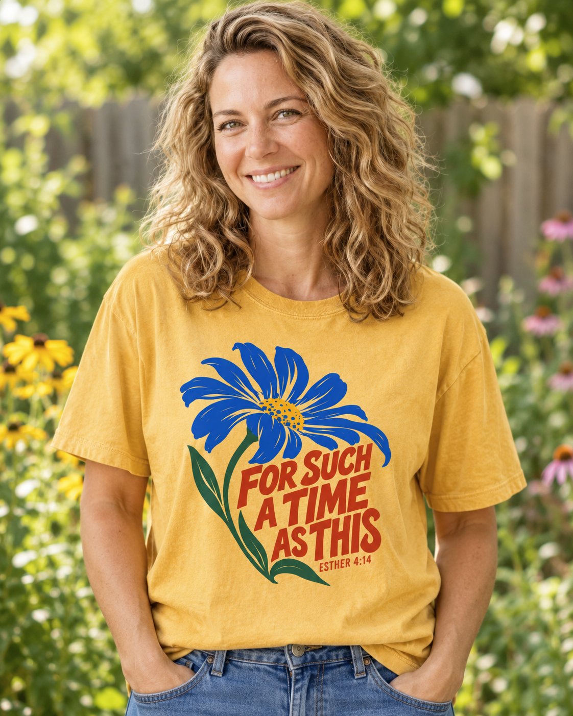 For Such a Time Daisy, Mustard women's Christian tee, lifestyle photo in outdoor garden, Blue daisy with red hand-lettered For Such A Time As This, She Wears Faith