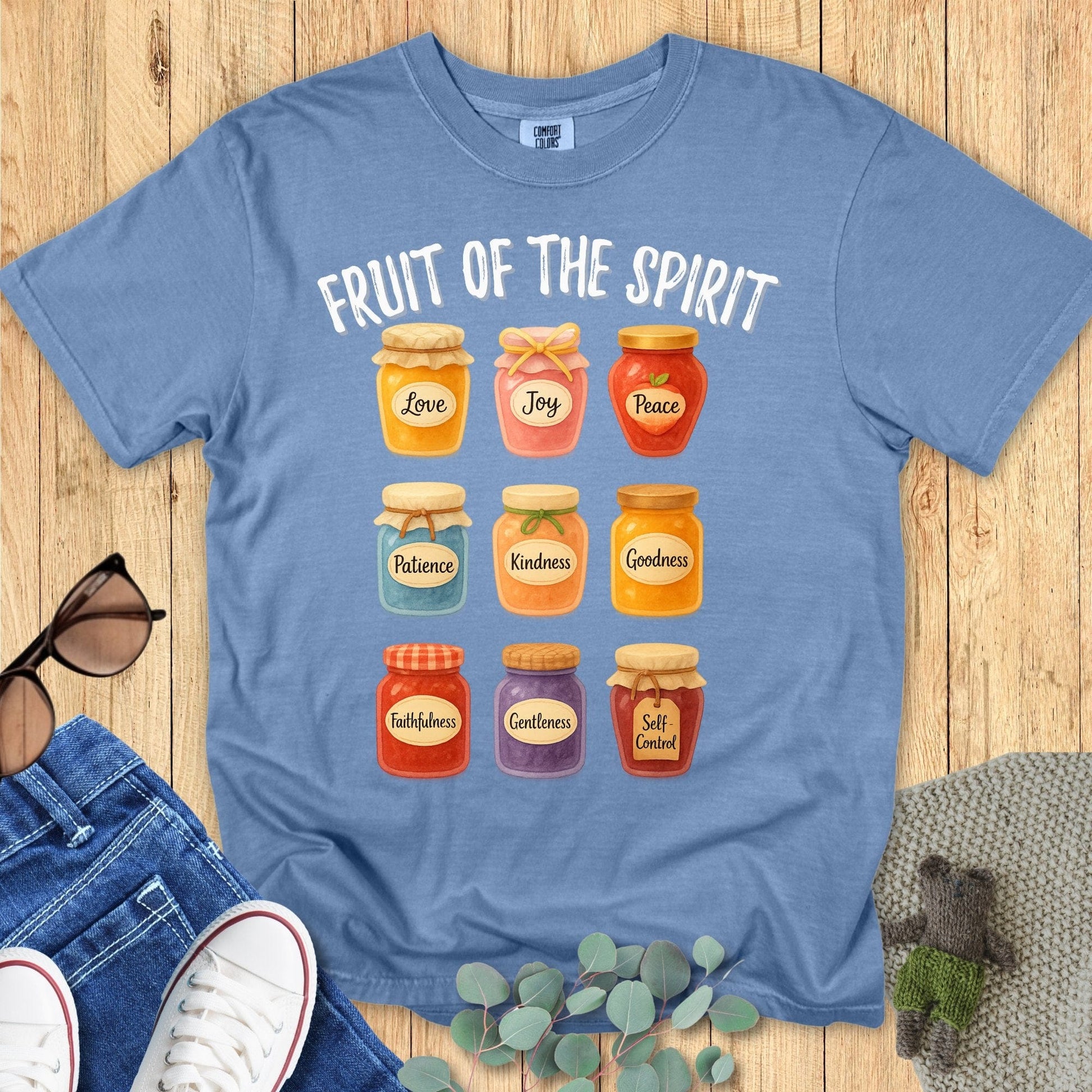Comfort Colors 1717 Christian women t-shirt in blue jean flat lay. Faith-based Fruit of the Spirit design featuring nine illustrated jars with words like Love, Joy, Peace, and Kindnes