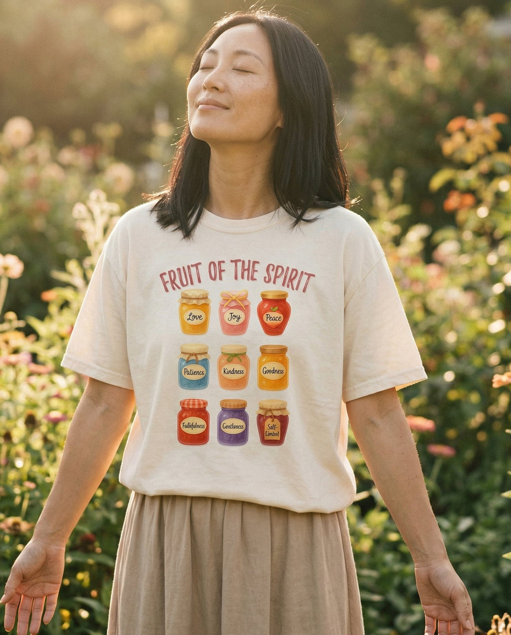 Fruit of the Spirit T-shirt – Ivory women's Christian tee, lifestyle photo in outdoor garden – Nine illustrated jam jars in warm colors – She Wears Faith
