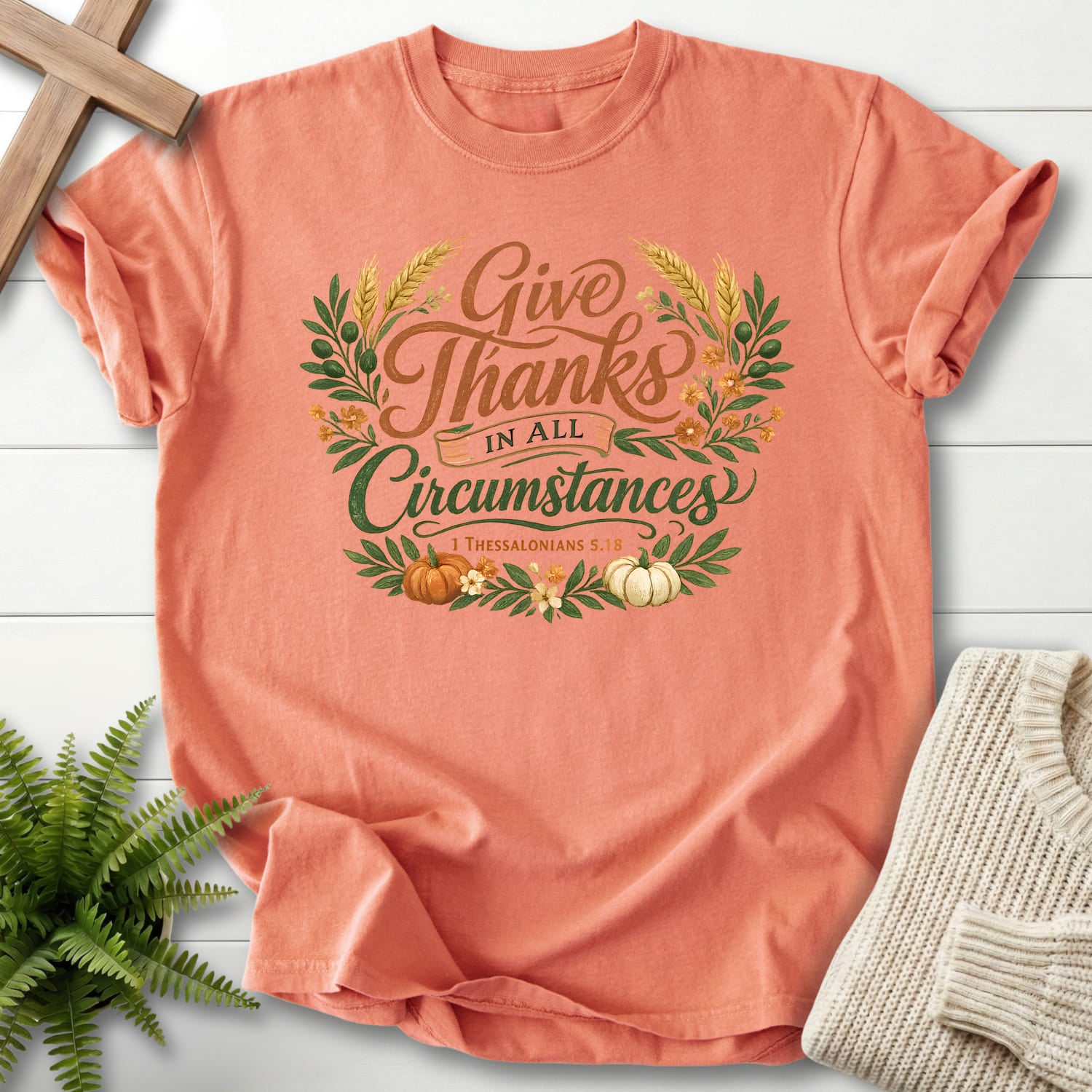 Flat lay of a Terracotta Scripture shirt featuring script typography with "Give Thanks in All Circumstances T-Shirt" 1 Thessalonians 5:18.