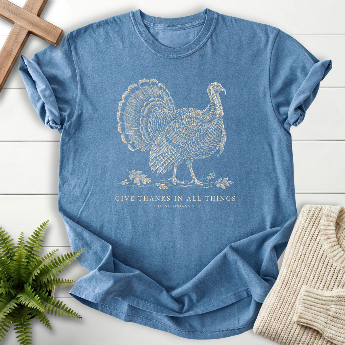 Flatlay of a Blue Jean women's Christian tee with "Give Thanks in All Things Turkey T-Shirt" 1 Thessalonians 5:18.