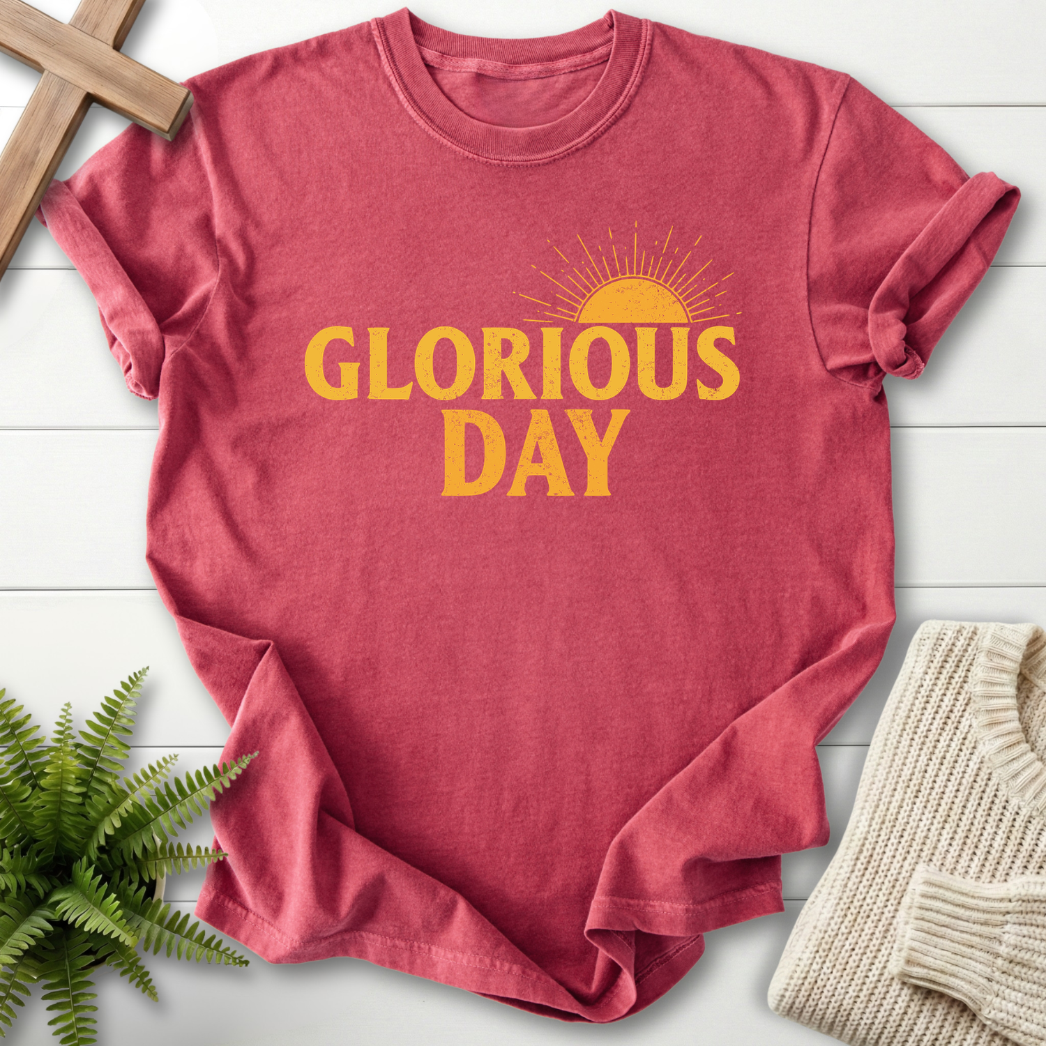 Crimson women's faith t-shirt with bold 'Glorious Day' text and a golden radiant sun graphic.